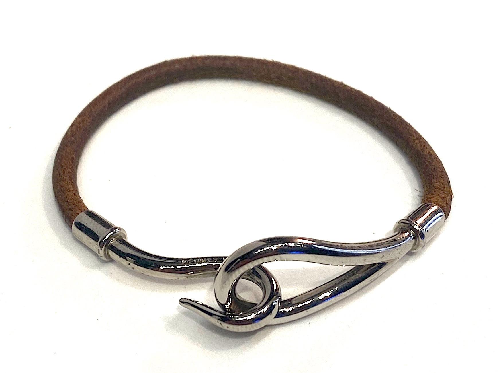 Hermes Jumbo Hook bracelet in cognac color leather cord with Palladium hardware. The Jumbo hook is inscribed Hermes. End to end the necklace measures 7.13 inches long. The eye end of the necklace is .69 on an inch wide. Very nice condition.