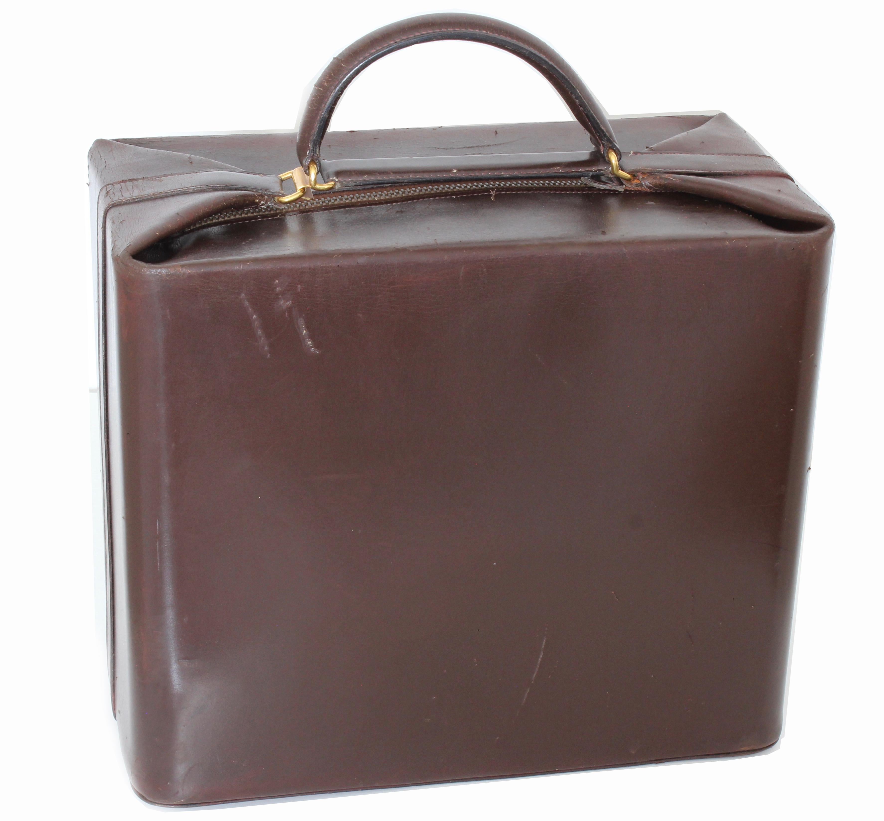 This extremely rare train case or vanity bag was made by Hermes, most likely in the early 1950s.  Made from brown box leather, it features a clasp under the top handle that reveals a long zipper to access the main compartment.  The interior