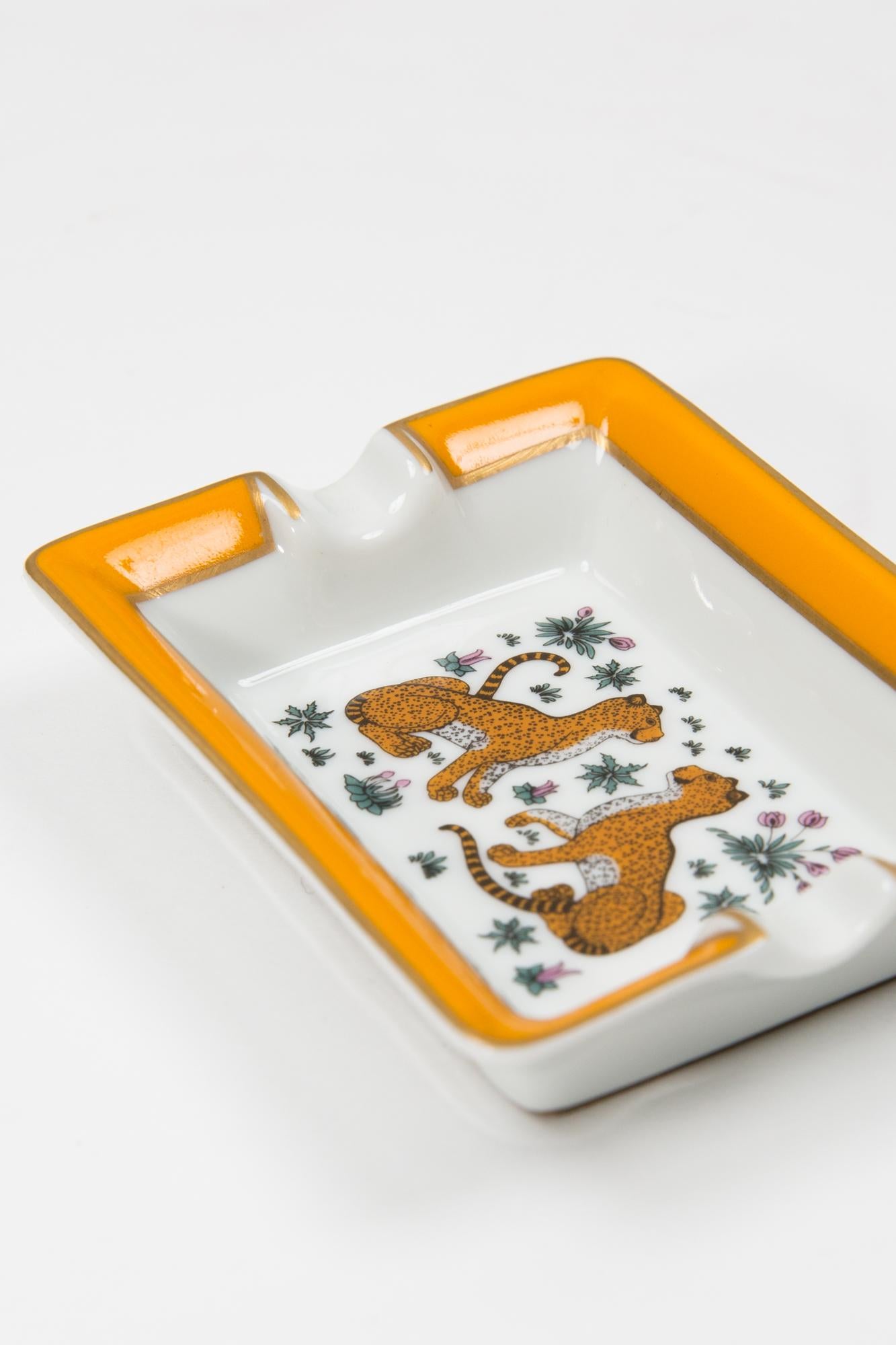 Hermès Leopard small size porcelain organizer or ashtray featuring an iconic Léopard center motive, a yellow border, a gold brush finishing, an under leather bottom, a Hermes gold-tone side signature.  
Circa 1980s 
In good vintage condition. 
Maxi