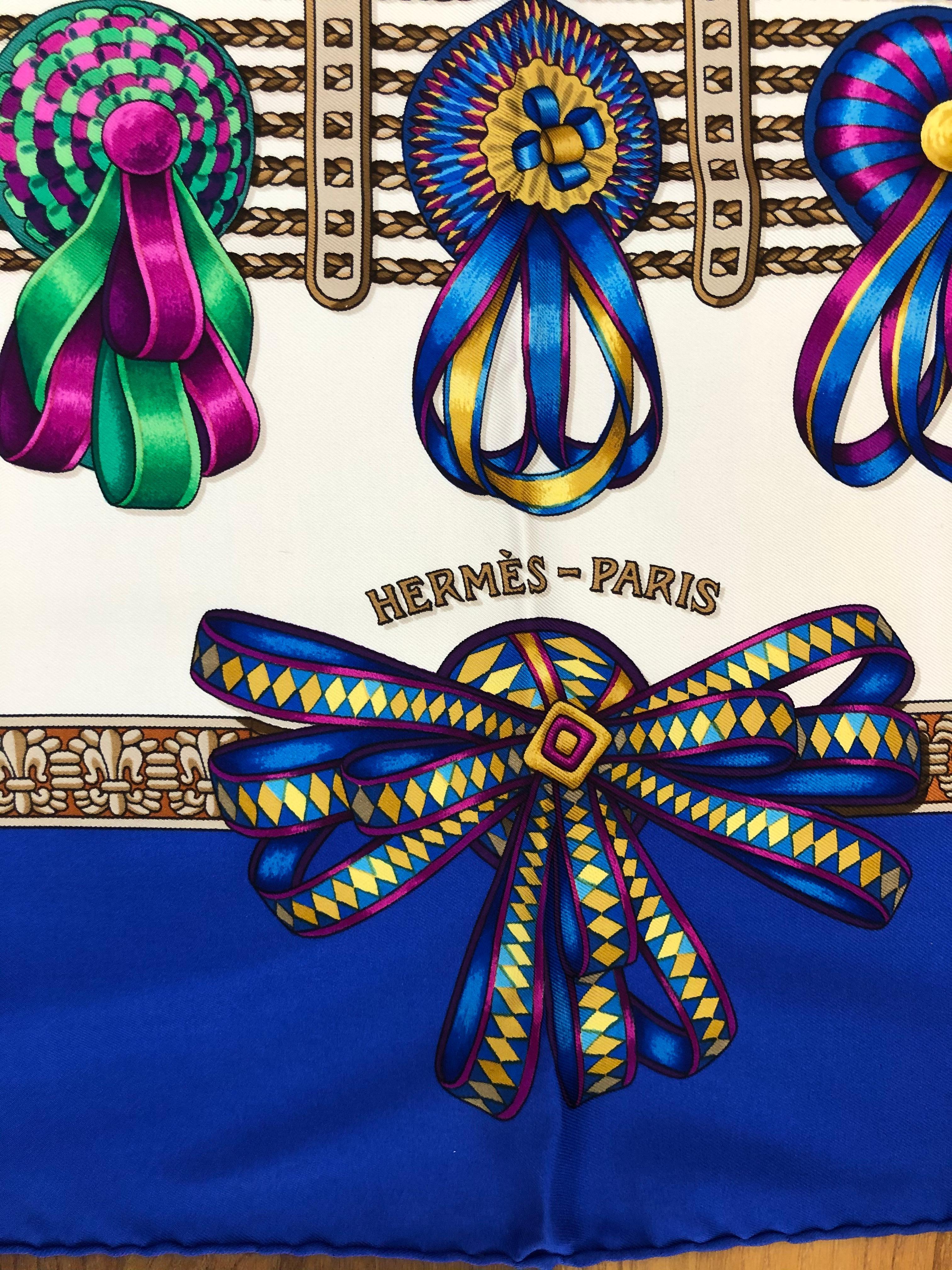 1993 silk scarf designed by Joachim Metz, the scarf is in excellent condition. The graphics feature very colorful equestrian ribbons over a white background and a blue border. The hand rolled hems are nice and plump, and the care tag intact. This