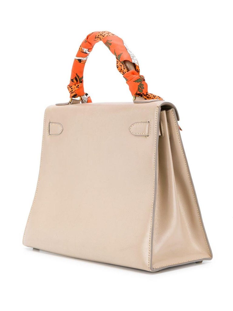 Crafted in France from box calf leather, a premium Hermès hide known for its soft glossy look and smooth texture, this structured, vintage bag features rigid corners and exterior stitching with concealed piping. Featuring a light grey exterior, this