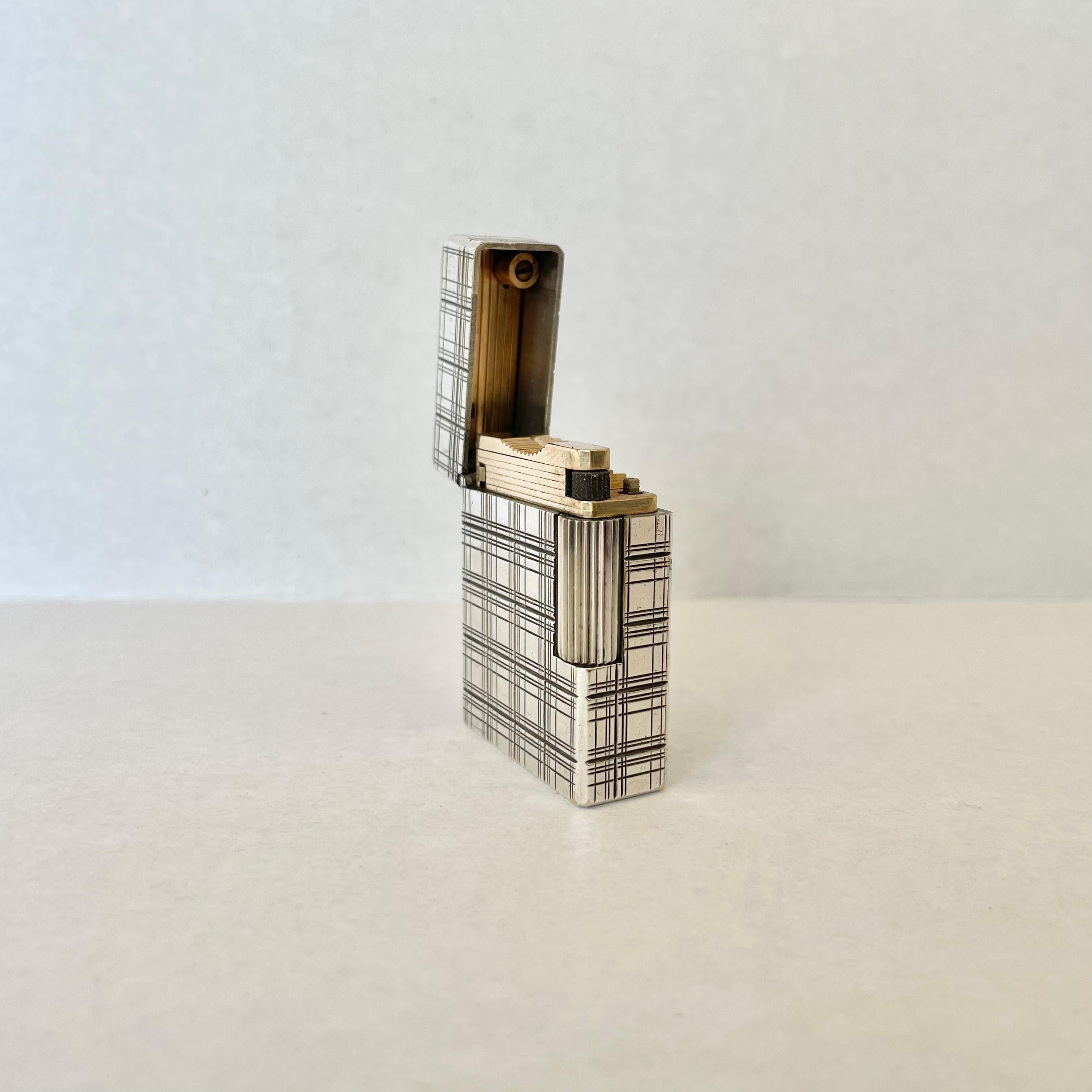 Elegant Dupont Lighter made for Hermes in the 60s. Perfectly joined heavy metal casing with brass lighting mechanism. Plaid windowpane design engraved on exterior with a blackened patina giving this piece great texture. 