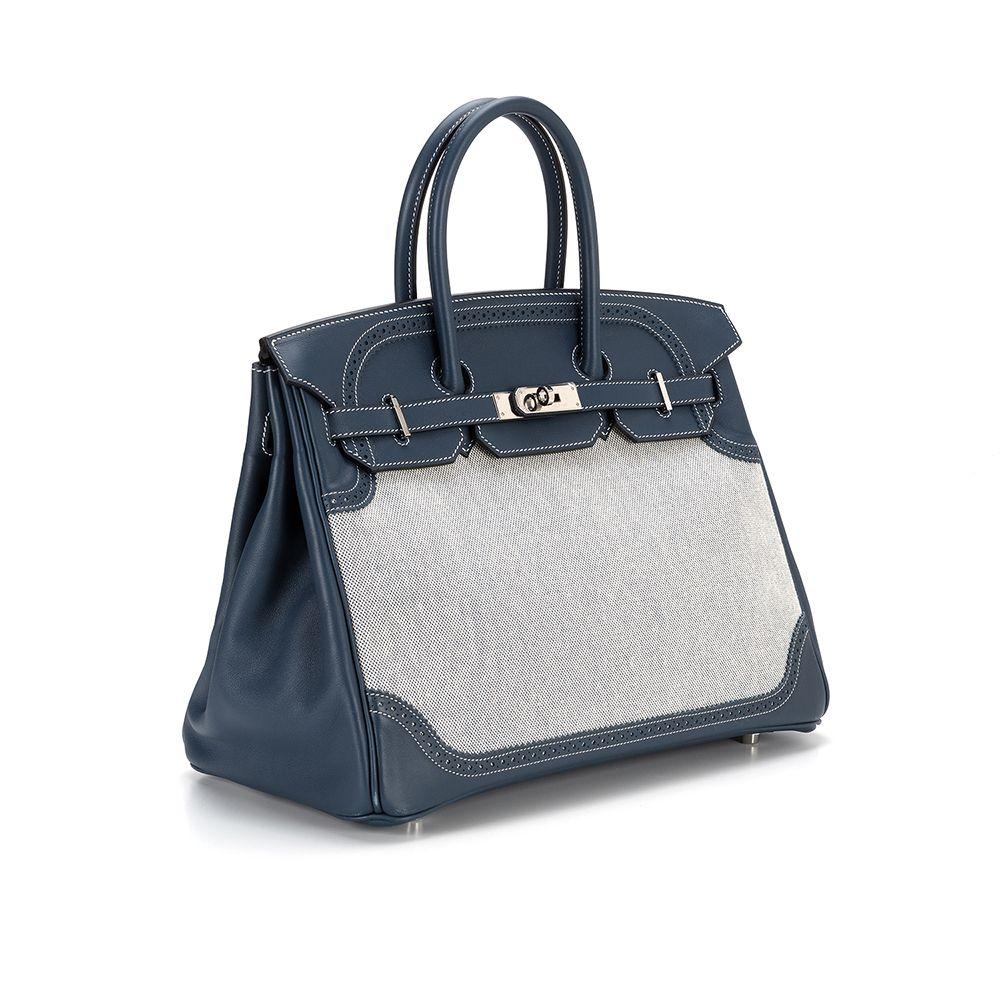 Invest in a very rare and limited edition piece with this Hermès Birkin, crafted in luscious Bleu de Prusse Swift Leather and Toile with Palladium Hardware, featuring two rolled handles and a flap top with a turn lock closure. The interior is done