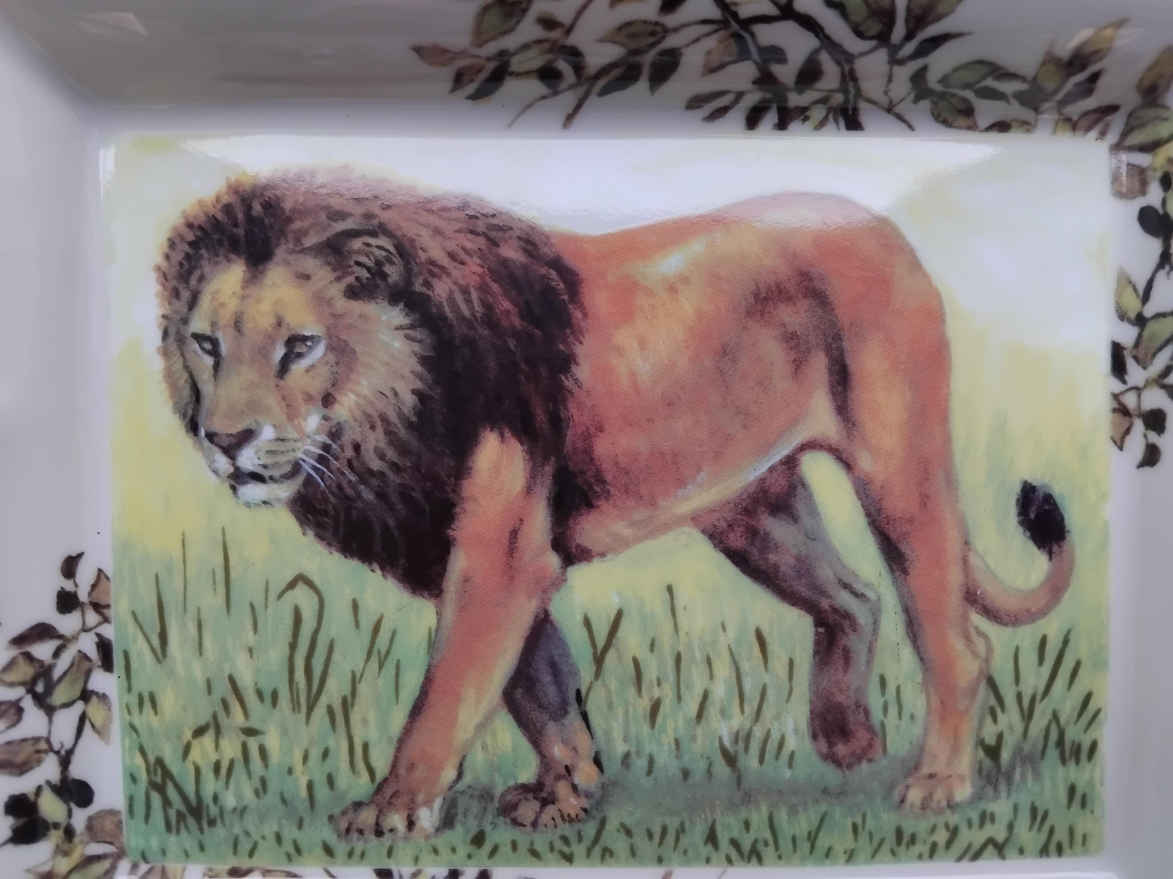 Gorgeous and Rare Authentic Hermès Ashtray

Print: Lion

Made in France

Made of porcelain, edges and notches hand painted with fine gold

Colorways: ivory, green, yellow, brown

Beige suede leather at bottom, 