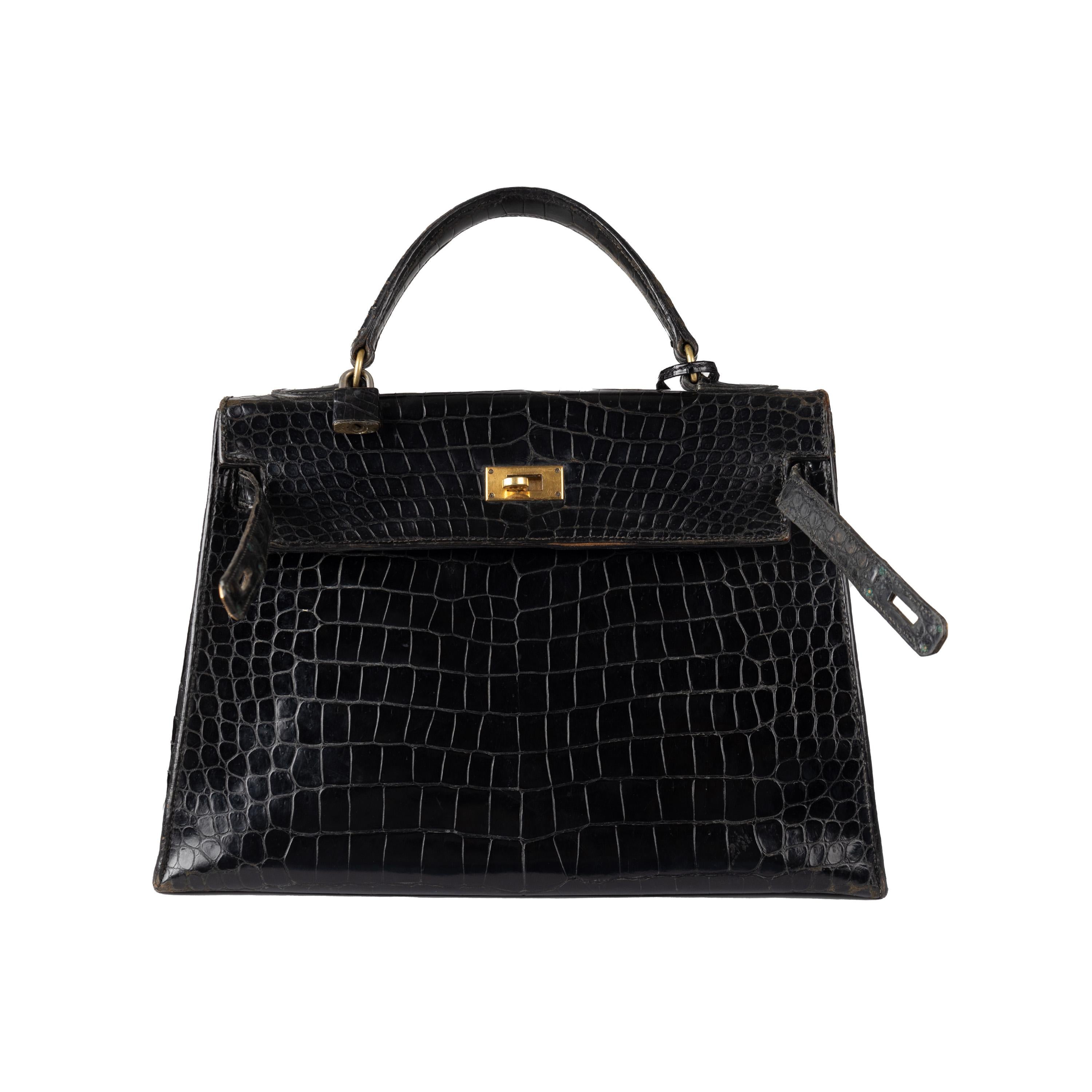 This rare and exquisite Hermès Lisse Crocodile Kelly 32 Retourne Handbag is a vintage treasure from the '60s. Crafted from Porosus Crocodile Lisse with a special agate polishing technique to make its glossy black exterior shine, its gold plated