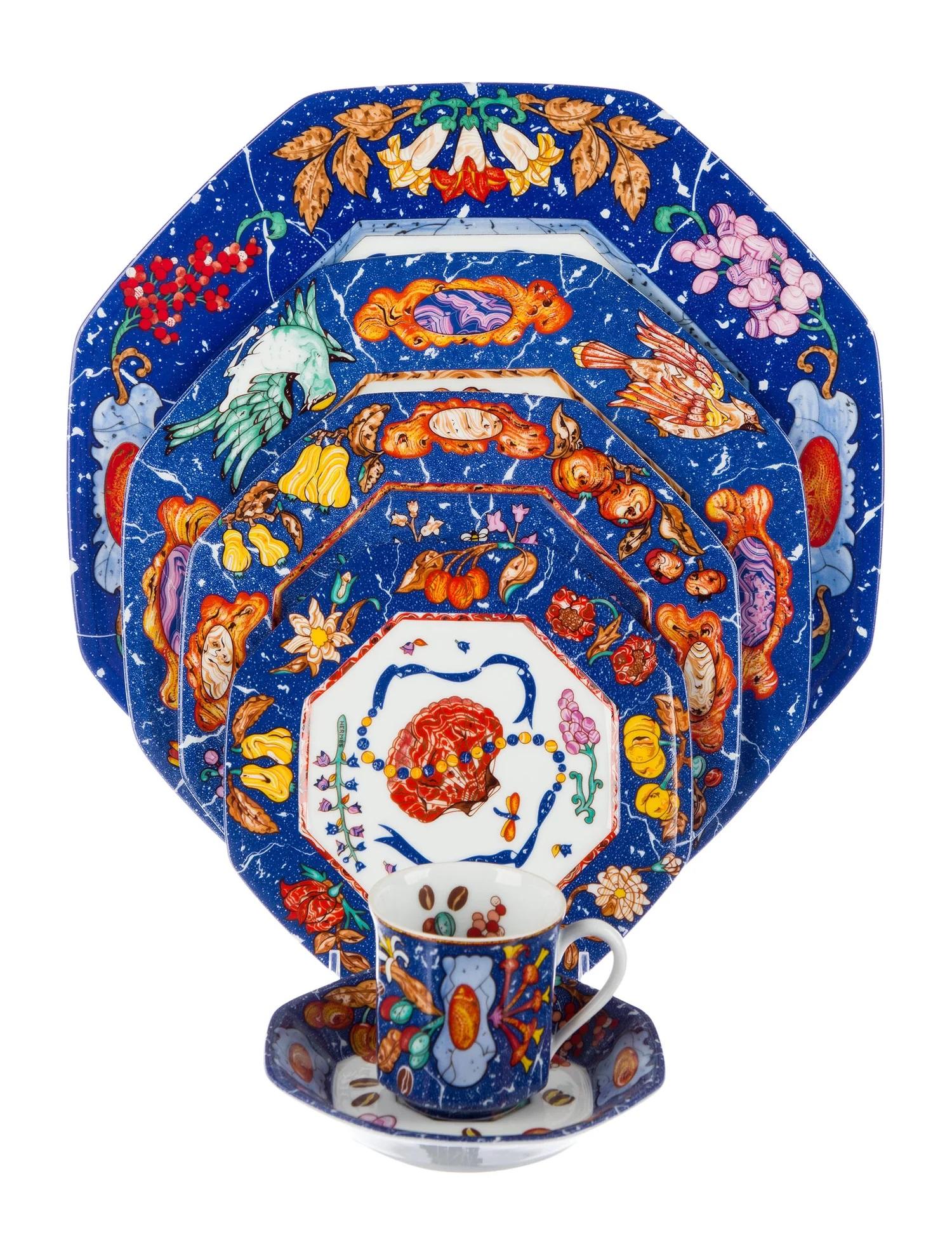 Ein 25-teiliges Tafelservice mit dem Muster Marqueterie de Pierres d'Orient et d'Occident von Hermès.

Mit weißem, blauem und mehrfarbigem Design mit Obst- und Blumenmotiven, getäfelten Wänden an den Außenseiten und Brandstempel an den