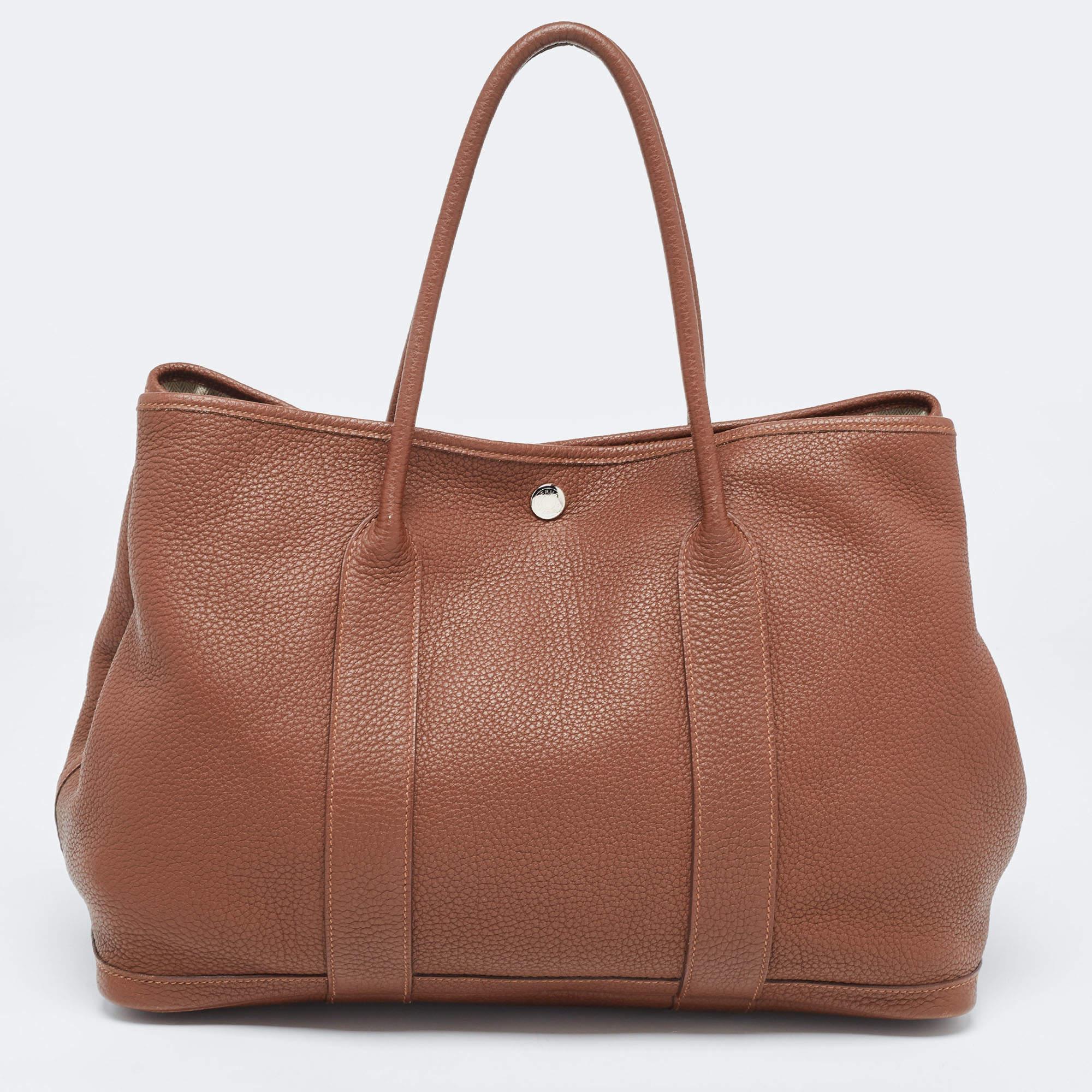 This Hermes Garden Party 36 promises to take you through the day with ease, whether you're at work or out and about in the city. From its design to its structure, the leather bag promises charm and durability. It has top handles, metal buttons, and