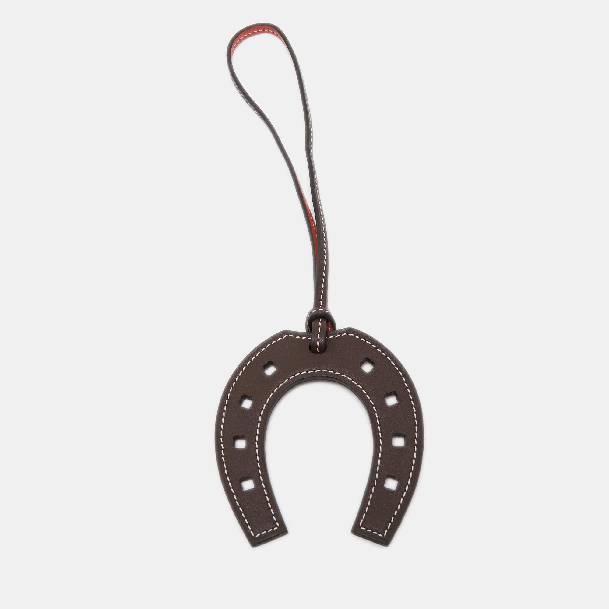 Paying homage to its equestrian heritage, this 'Paddock Fer a Cheval' bag charm from Hermes is a classy accessory to own. It is crafted using Swift leather and hangs from a strap. Needless to say, this Hermes bag charm will add a signature touch to