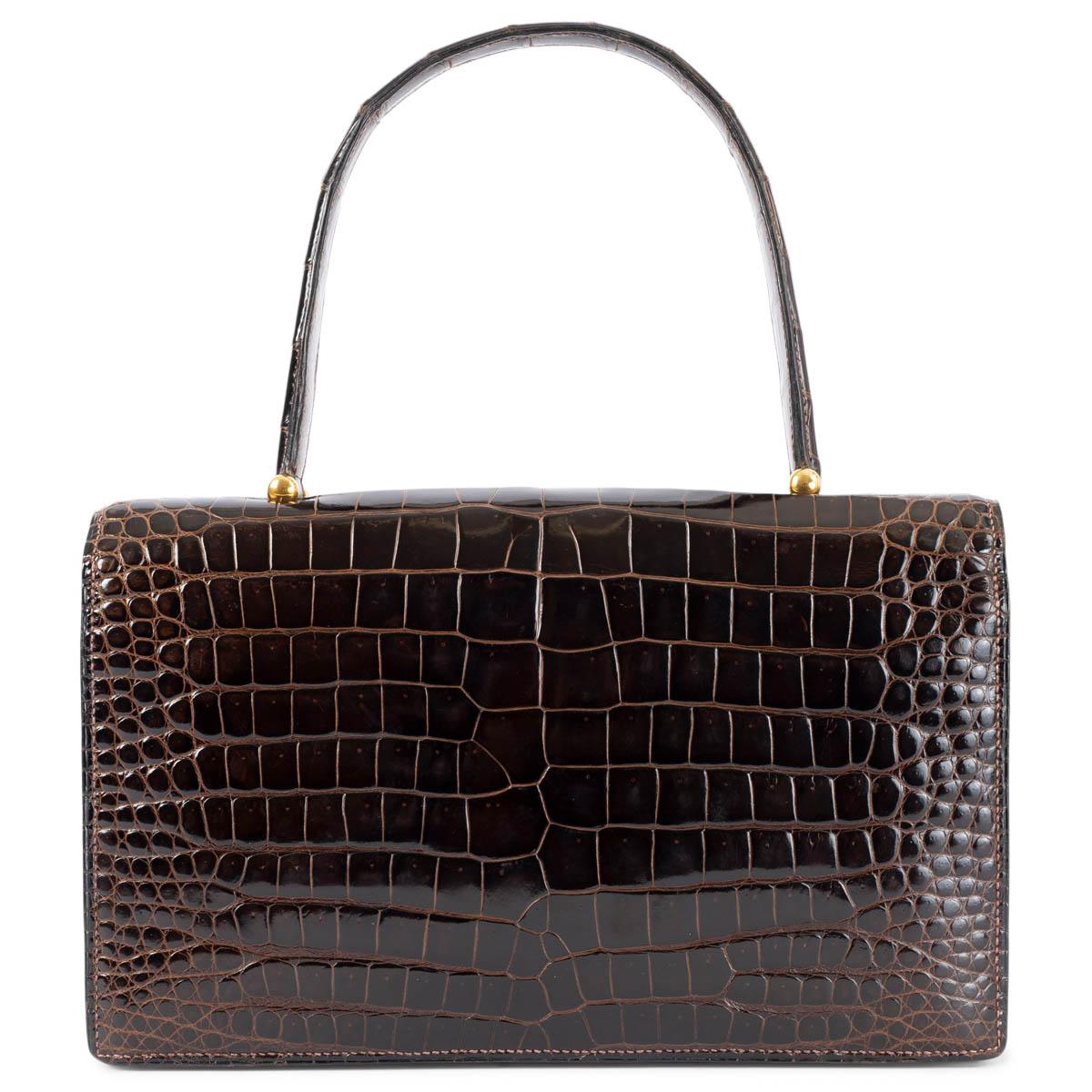 100% authentische Hermès Boutonnière Tasche aus Marron Fonce (braun) Krokodil mit goldfarbenen Beschlägen. Das Design verfügt über eine Schlitztasche unter der Klappe und das Innere ist in zwei Fächer mit zwei aufgesetzten Taschen und einer