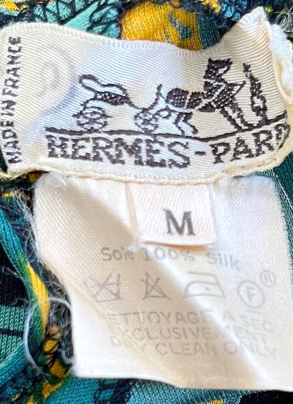 Rare and collectible vintage F/W 96 HERMÈS silk jersey bodysuit ! Artist Hugo Grygkar designed this print, naming it “Biblotheque” 
Vibrant hues of green, with exciting book prints throughout. Gold logo button at back center neck.
Great with jeans,