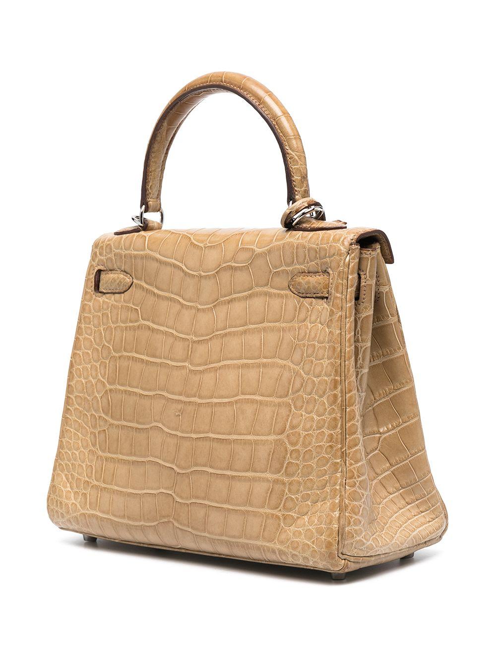 Expertly crafted in France from a matte Poussiere Alligator Mississippiensis leather, a favoured Hermès hide for its large, square, rougher ridged scales and durability against scuffing and scratching, this Hermès Kelly Retourne bag is a true
