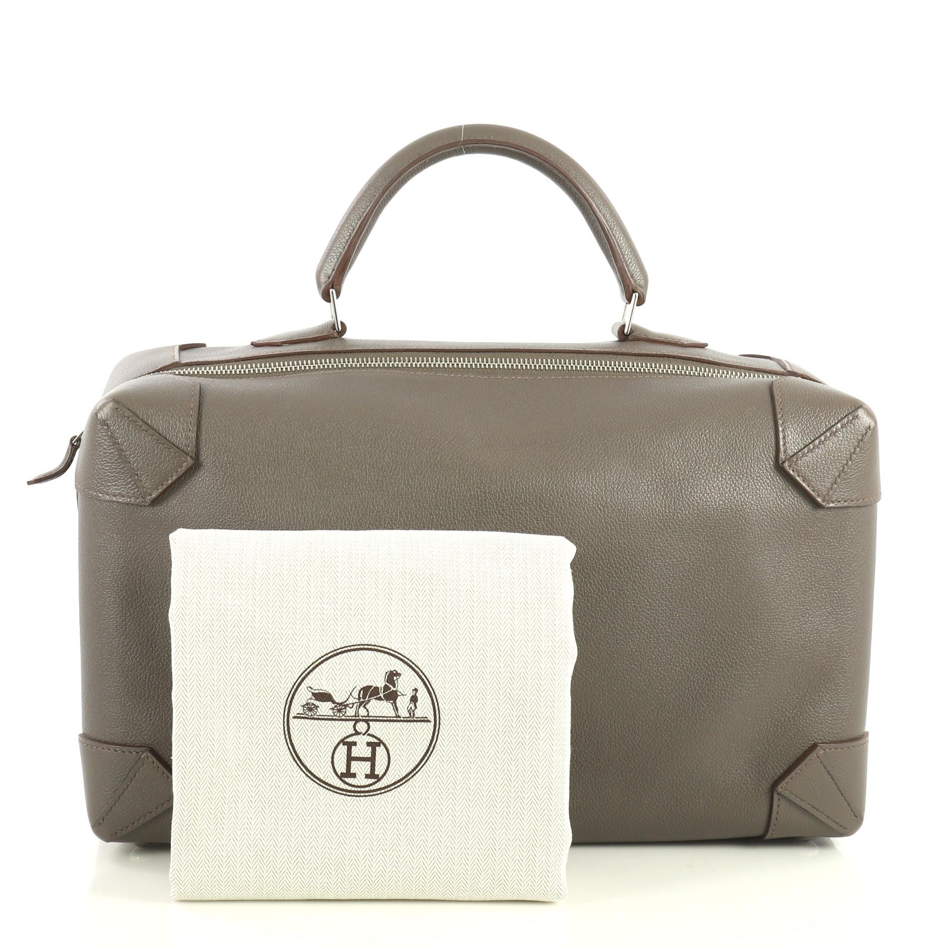 This Hermes Maxibox Handbag Evercolor 37, crafted in Etain neutral Evercolor leather, features a rolled leather handle and palladium hardware. Its zip closure opens to an Etain neutral Chevre leather interior with zip and slip pockets. Date stamp