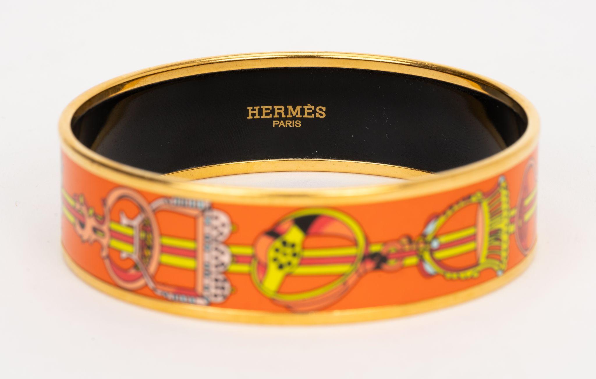 Il bracciale Hermès Enamel Bangle è caratterizzato da una stampa a staffa in arancione e oro. Ottime condizioni, viene fornito con la custodia originale.