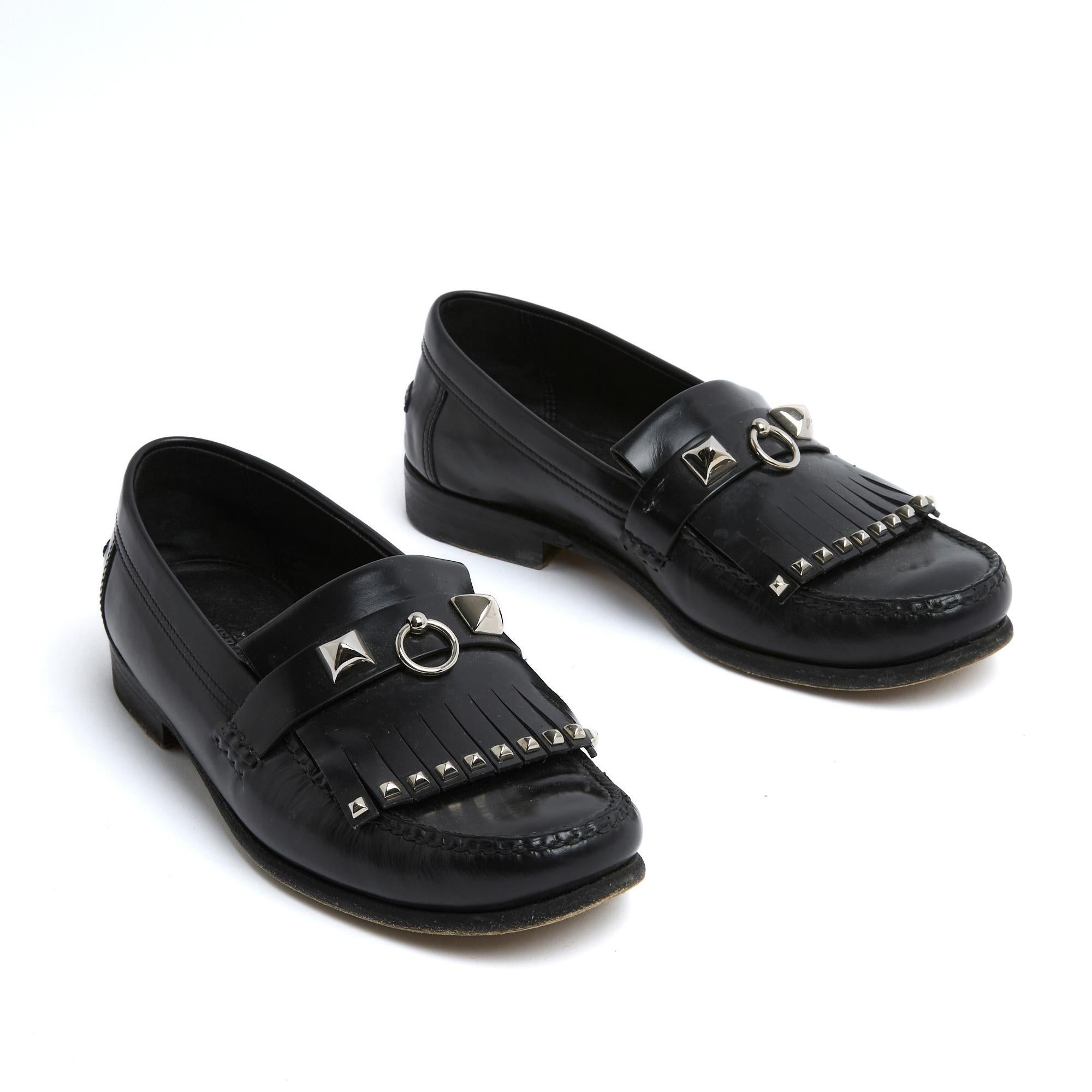 Mocassins Hermès en cuir box noir rehaussé de clous et d'anneaux du modèle Collier de Chien ou Médor, frange ornée de mini clous sur le devant, intérieur et dessous en cuir. Taille EU37 (UK4 et US6.5), talon 2 cm, semelle intérieure 23.7 cm. Les