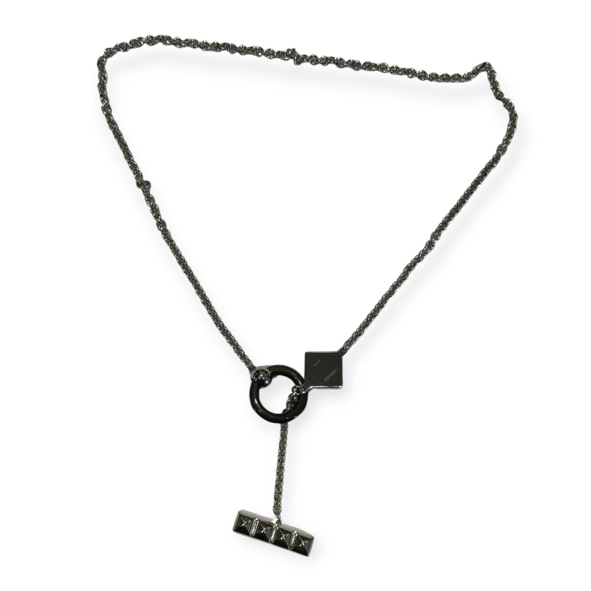Die Hermès XO Halskette zeichnet sich durch eine komplizierte Metallspitze und einen einzigartigen Charme aus Horn aus, der von dem Ring des Collier de Chien inspiriert ist. Das 