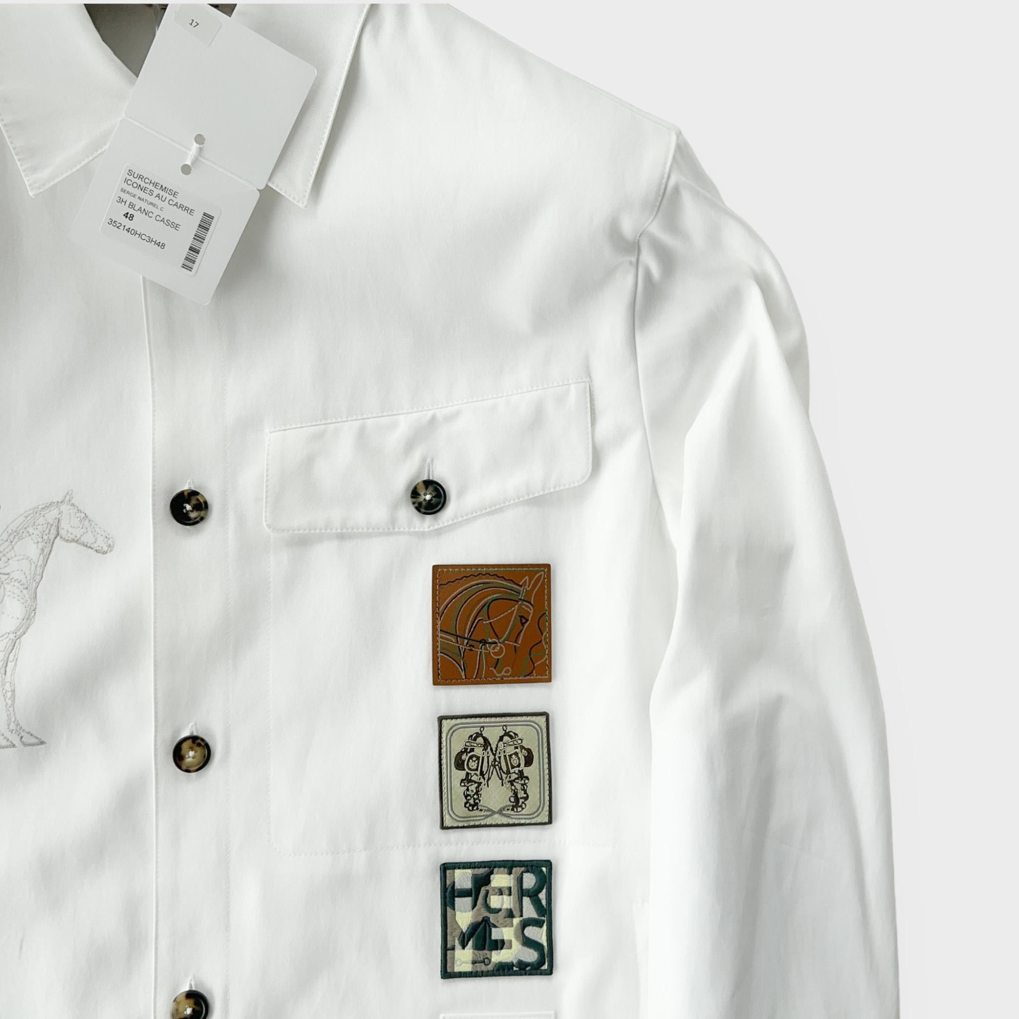 Shop this Men's 'Icones au Carre' Straight Cut Overshirt from the Hermes Spring / Summer 2023 collection. It comes in the Blanc Cassé colour way and features the new season 'Icones au Carre' detailing.

The jacket is made from 54% Viscose and 46%