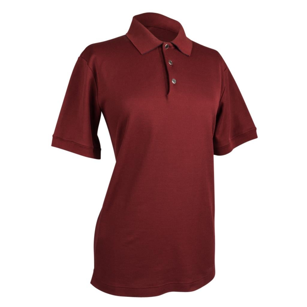 Guaranteed authentic Hermes men's Rouge H with Navy Edging polo style shirt.
Contrasting Navy edging on collar, sleeve and on vents.
Short sleeve shirt with 3 silver Clou de Selle buttons. 
Ribbing around sleeves.
Fabric is cotton and polyester.