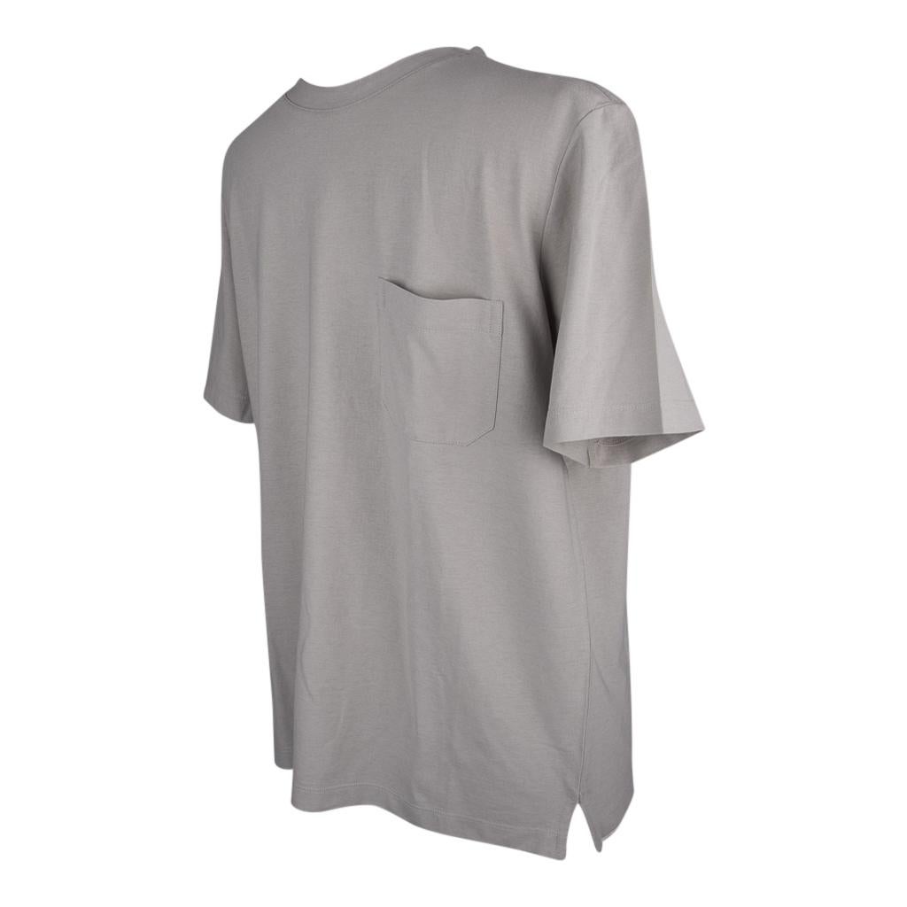 Guaranteed authentic Hermes Grey Tee shirt with breast pocket.
Crew Neck with short sleeve.
2 side vents.
Double stitch detail on shoulder.
Classic style and effortless elegance.
Fabric is cotton. 
NEW or NEVER WORN 
final sale

SIZE  M

TOP