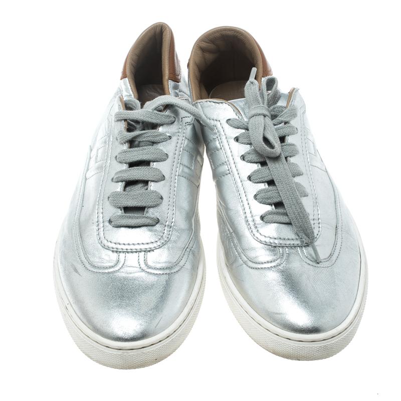 These Quicker sneakers from Hermes promise that you'll shine all day long and fetch compliments from one and all! These metallic silver sneakers are crafted from leather and feature round toes, lace-ups on the vamps and a stitched 'H' detailing on