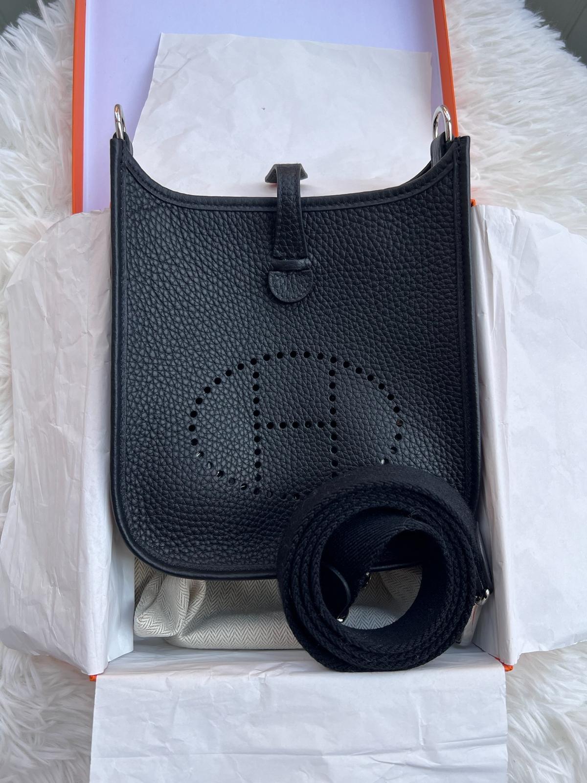 Bolso Hermes mini Evelyne 16 negro con correa negra. 
Este bolso, muy práctico y elegante, tiene una correa desmontable y puede llevarse colgado del hombro o cruzado.  Acabado metálico: herrajes paladio 
Dimensiones: L 16 x A 20 x P 5,5 cm  Longitud