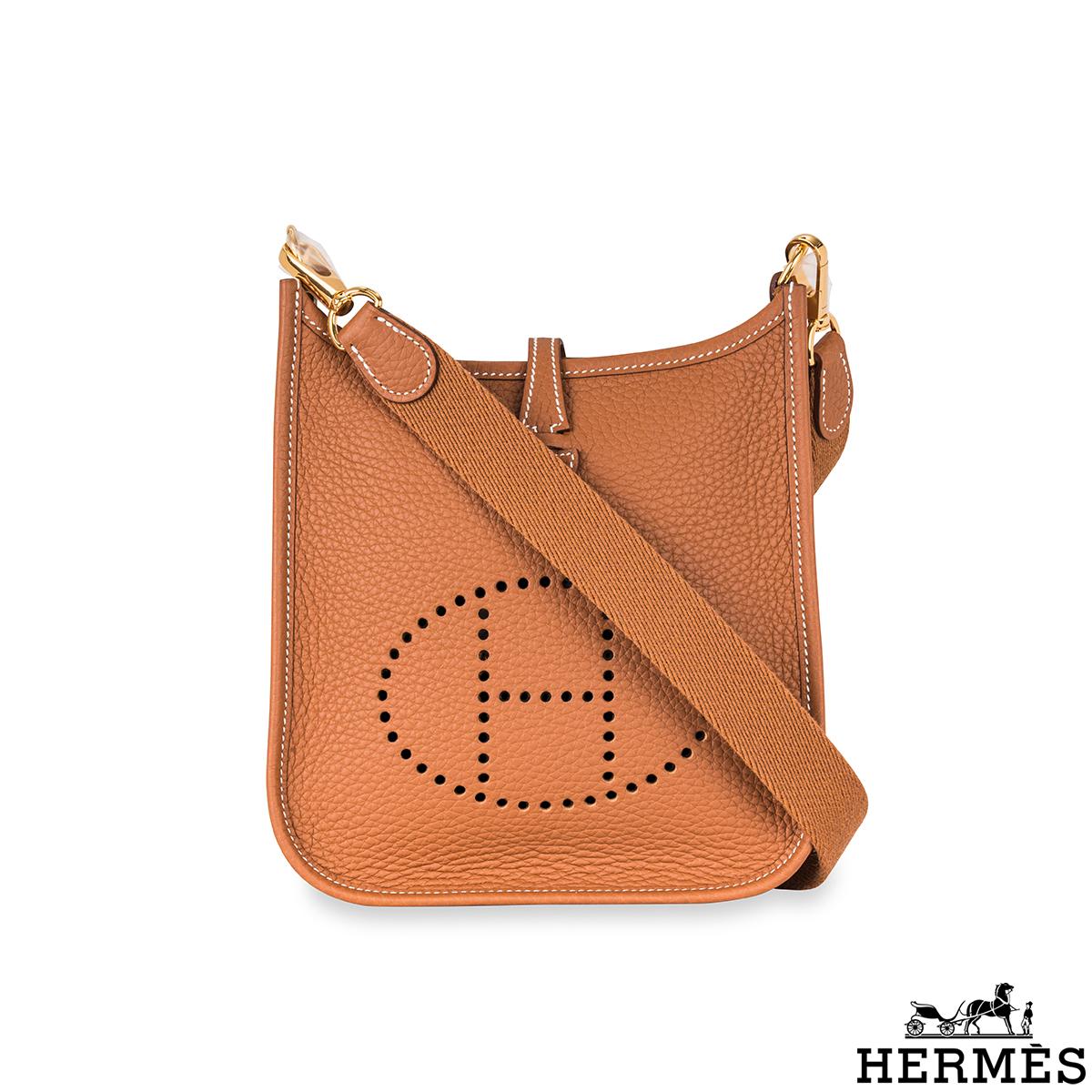 Eine schöne Hermès Mini-Handtasche Evelyne. Das Äußere dieser Evelyne-Tasche ist aus goldfarbenem Taurillon-Clemence-Leder gefertigt und wird durch goldfarbene Beschläge und weiße Nähte ergänzt. Sie verfügt über ein perforiertes 