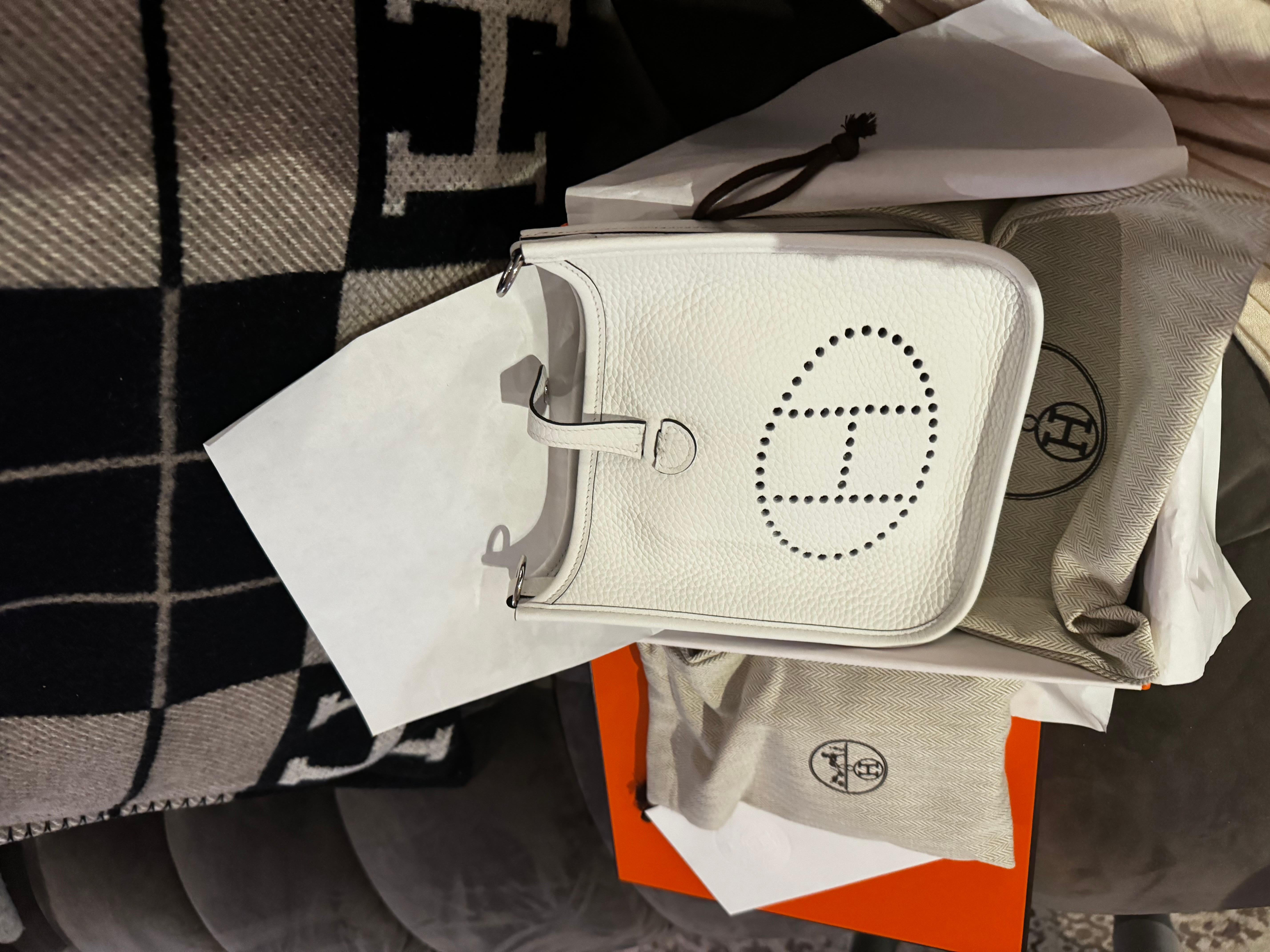 Hermes mini Evelyne bag in New White colour and palladium hardware. Comes with a crossbody canvas strap, dustbags and box as from the shop. B stamp end of 2023.