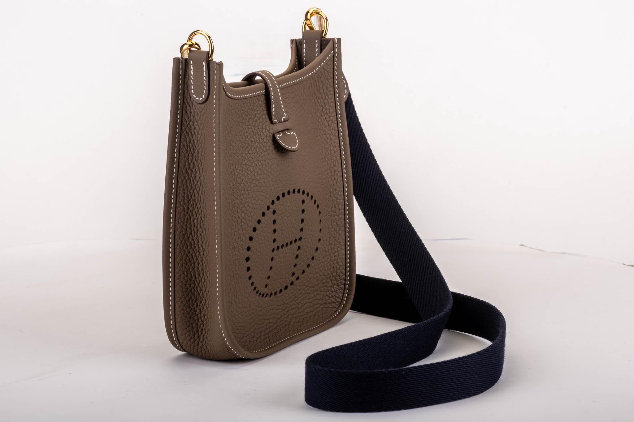 Hermès mini evelyne in etouoe clemence leather with gold tone hardware. Crossbody fabric strap in contrast navy color, 44