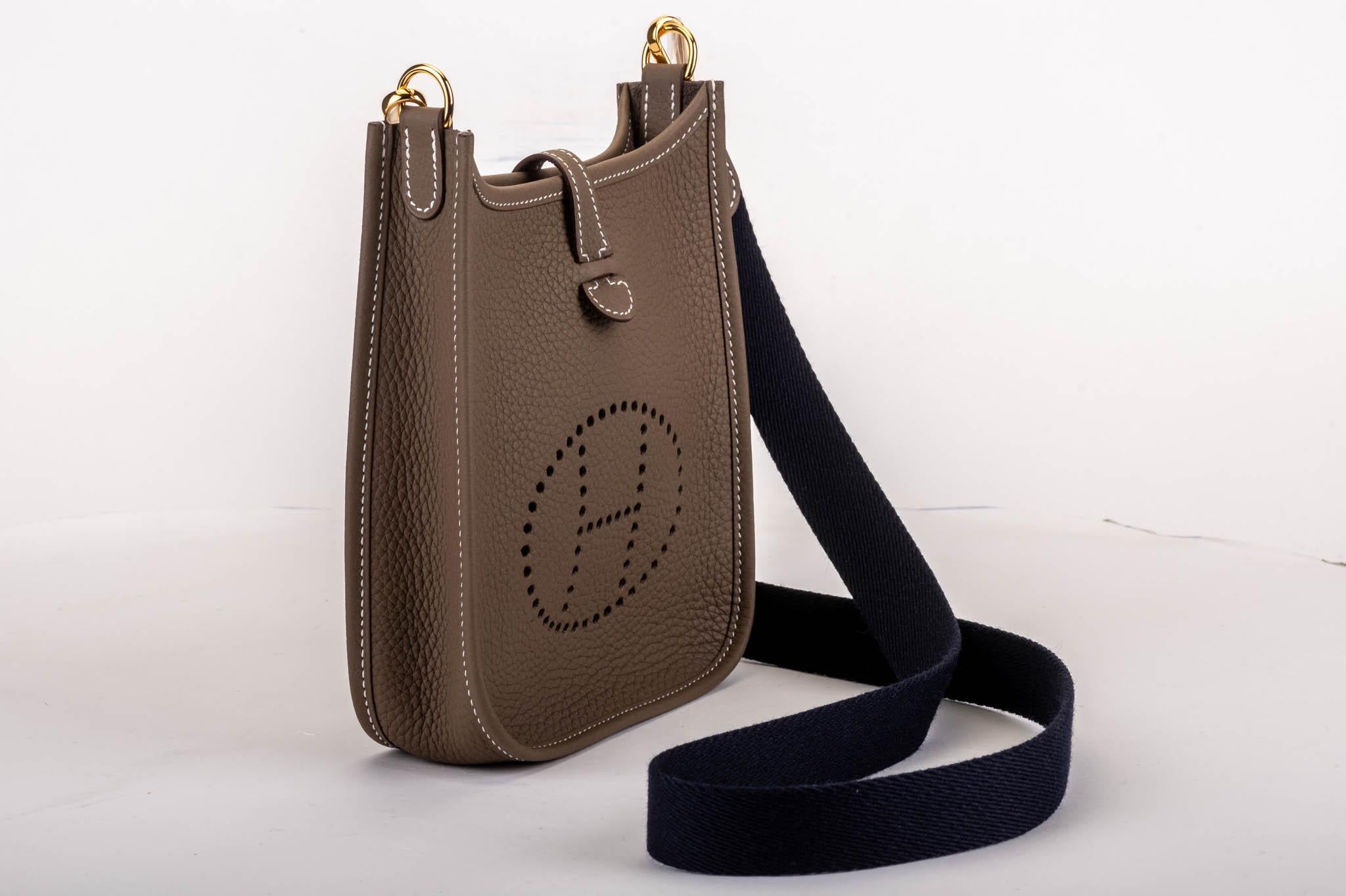 Hermès mini evelyne in etouoe clemence leather with gold tone hardware. Crossbody fabric strap in contrast navy color, 44