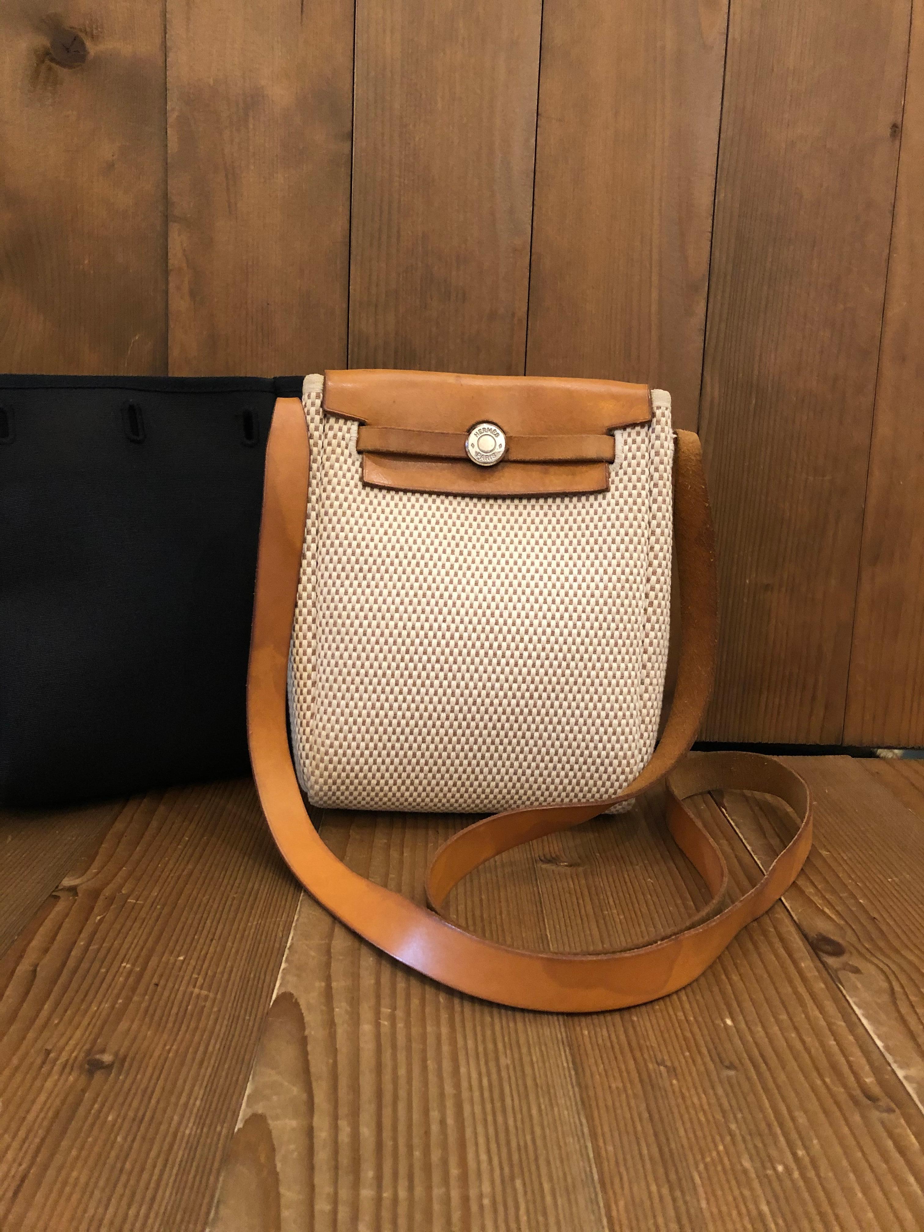 This is an authentic HERMES Herbag Toile PM natural and black crossbody bag. This compact two in one crossbody bag is crafted of cotton canvas (black and natural beige) and natural cowhide leather. The top crown alternates between bases of natural
