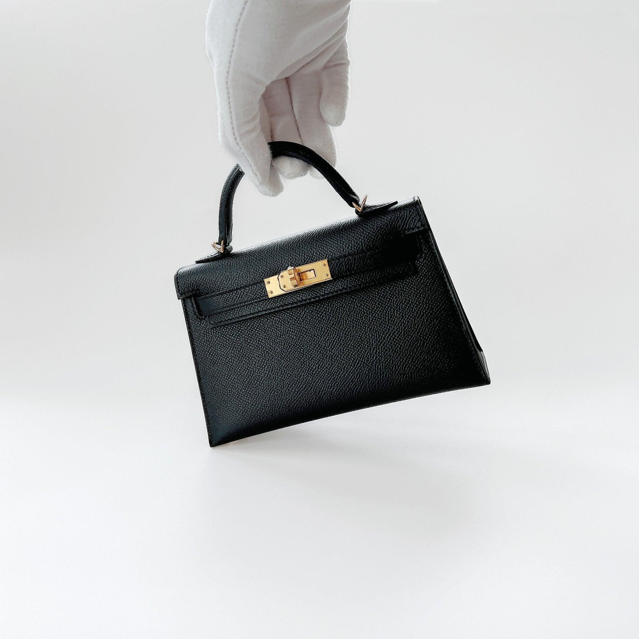Shop this classic Hermes Mini Kelly In Black With Gold Hardware, Epsom Leather. This Hermes Mini Kelly II comes in Sellier Epsom Leather making it hold its shape. The base has 4 gold plated feet to prevent scratching to the bottom of the bag. This