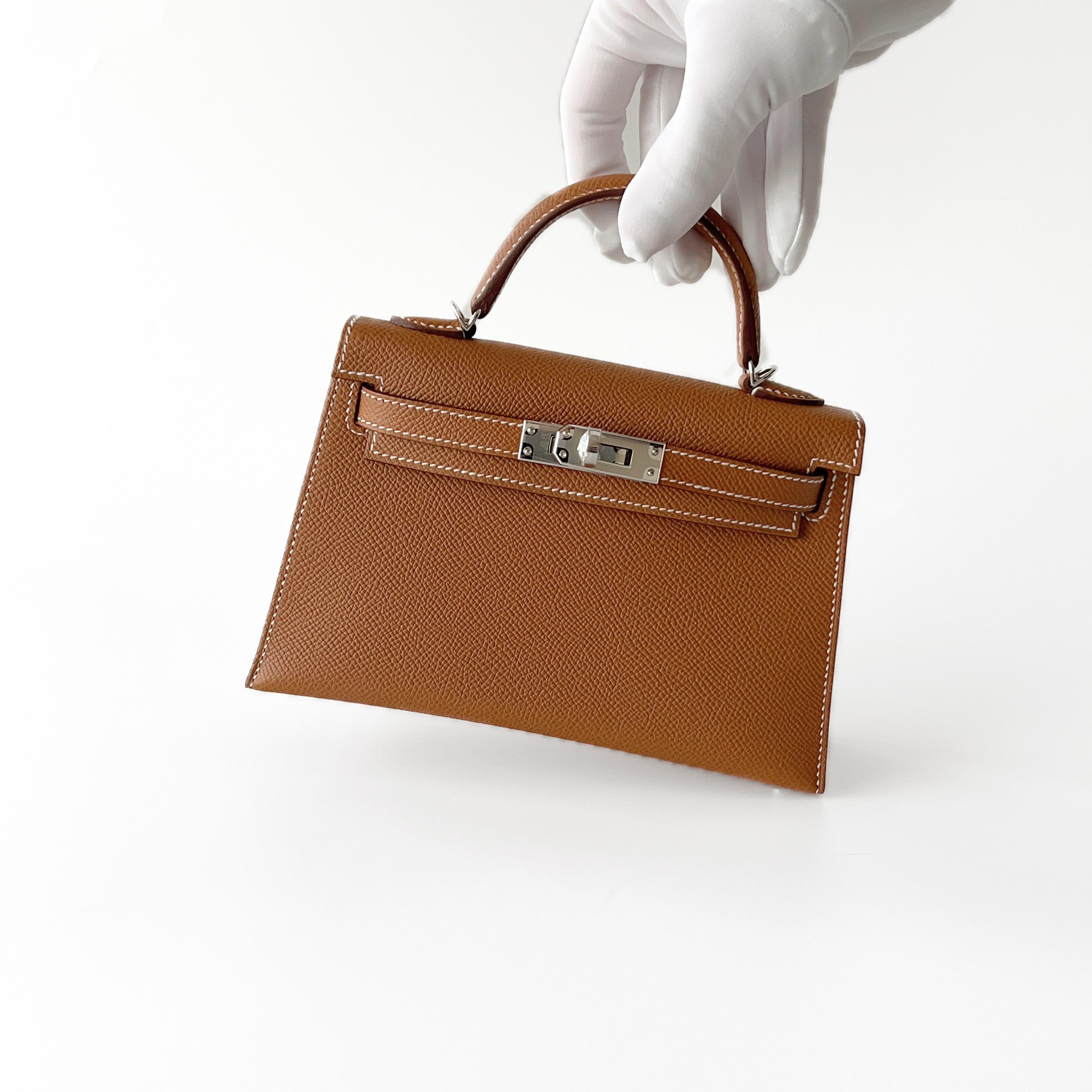 Shop this classic Hermes Mini Kelly In Gold With Palladium Plated Hardware, Epsom Leather. This Hermes Mini Kelly II comes in Sellier Epsom Leather making it hold its shape. The base has 4 palladium plated feet to prevent scratching to the bottom of