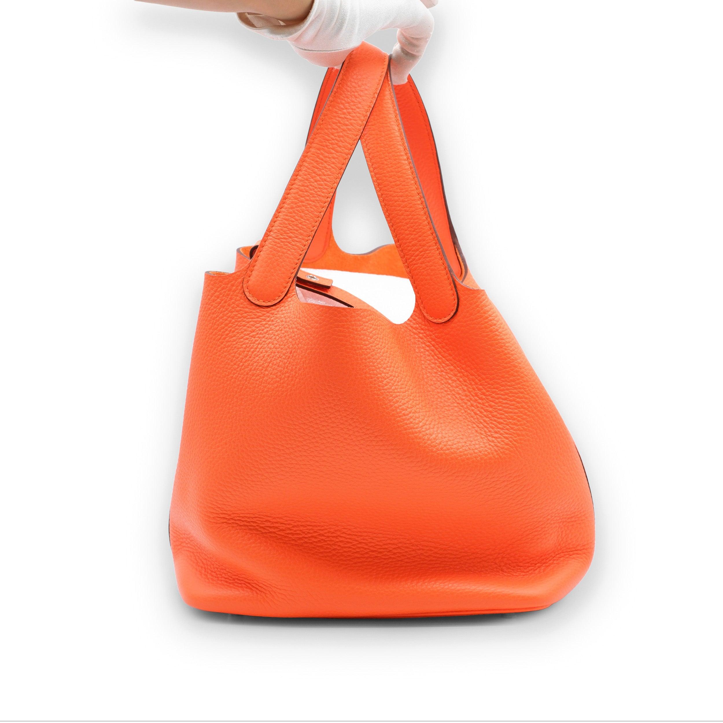 This Picotin 22 is made of clemence Orange Minium leather with palladium trim and features tonal stitching with two top handles.
 The interior is lined in natural Orange Minium leather, with no interior pockets and a padlock closure.
 Inclusions: