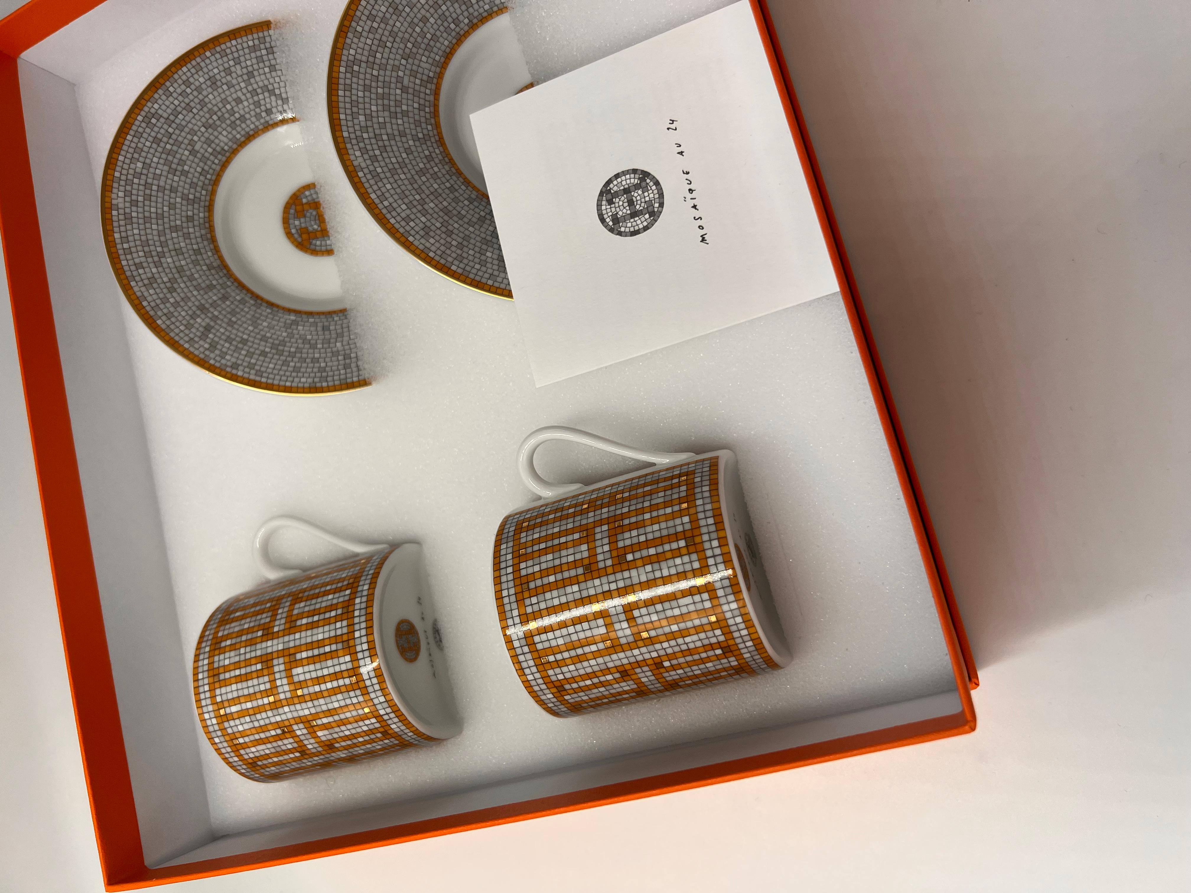 Set of 2 gold, grey and white porcelain Hermès Mosaïque Au 24 coffee cup and matching saucer with tile design throughout, gilt accents and brand stamp on the bottom. Brand new in a box. 