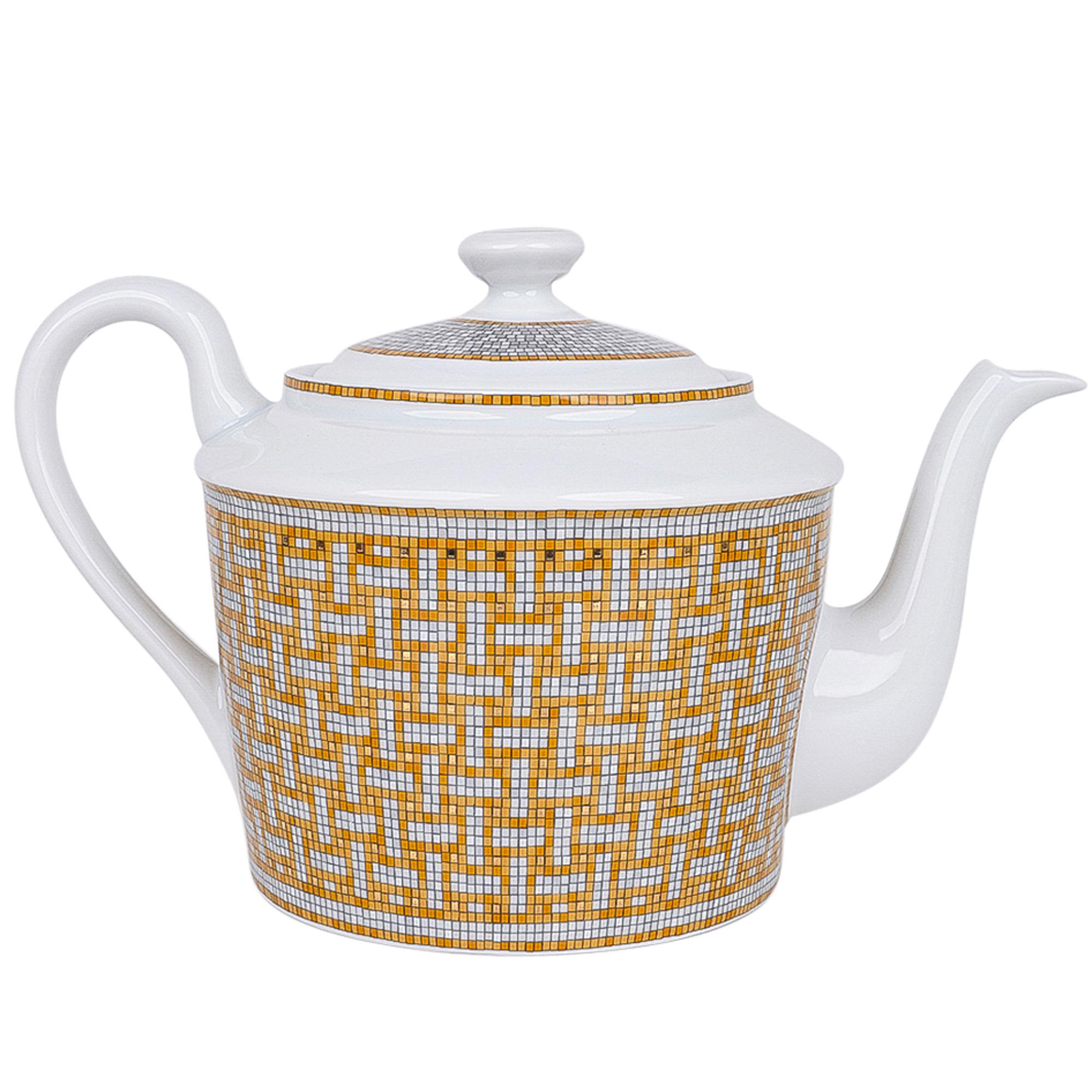 Guaranteed authentic Hermes Mosaique Au 24 Gold teapot with four teacups and saucers.
This beautiful porcelain Hermes Mosaique tea set creates a perfect setting for any table.
Inspired by the setting of the Paris Hermes flagship store 24 Faubourg