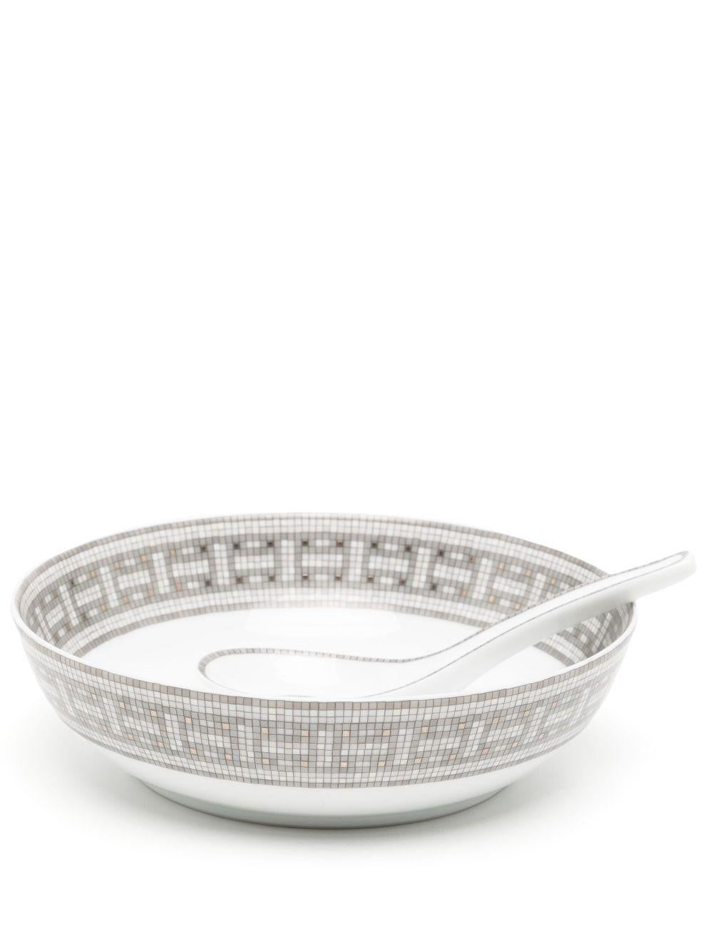 Bowl and spoon set from Hermès with a tonal grey mosaic adorning the rim. Handcrafted from white porcelain. This set is in excellent condition with no signs of damage or use.