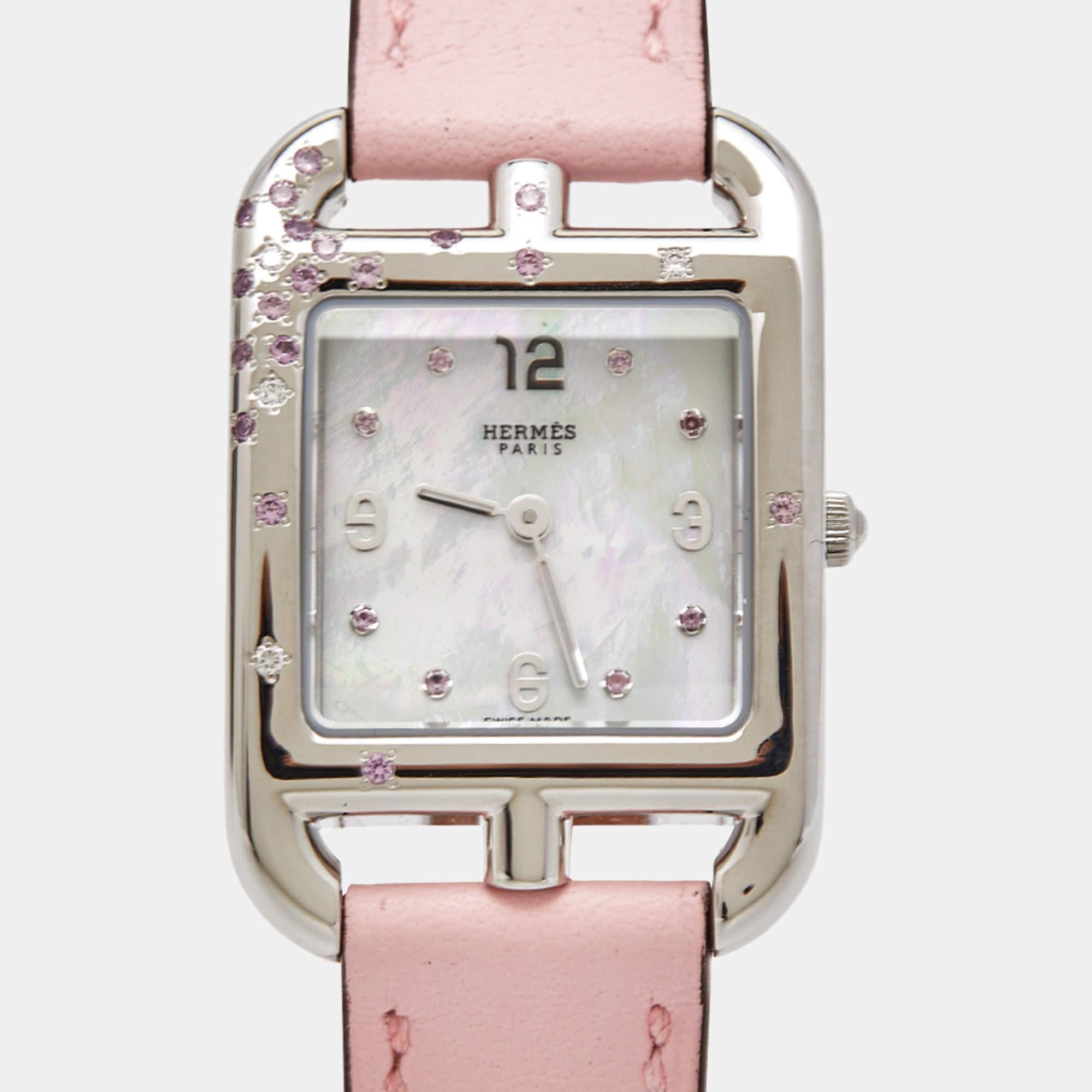 The Hermès wristwatch, model W052160WW00, is an exquisite timepiece designed for sophistication and elegance. Its stainless steel case boasts a lustrous mother-of-pearl dial adorned with sparkling diamonds and pink sapphires, exuding opulence. The