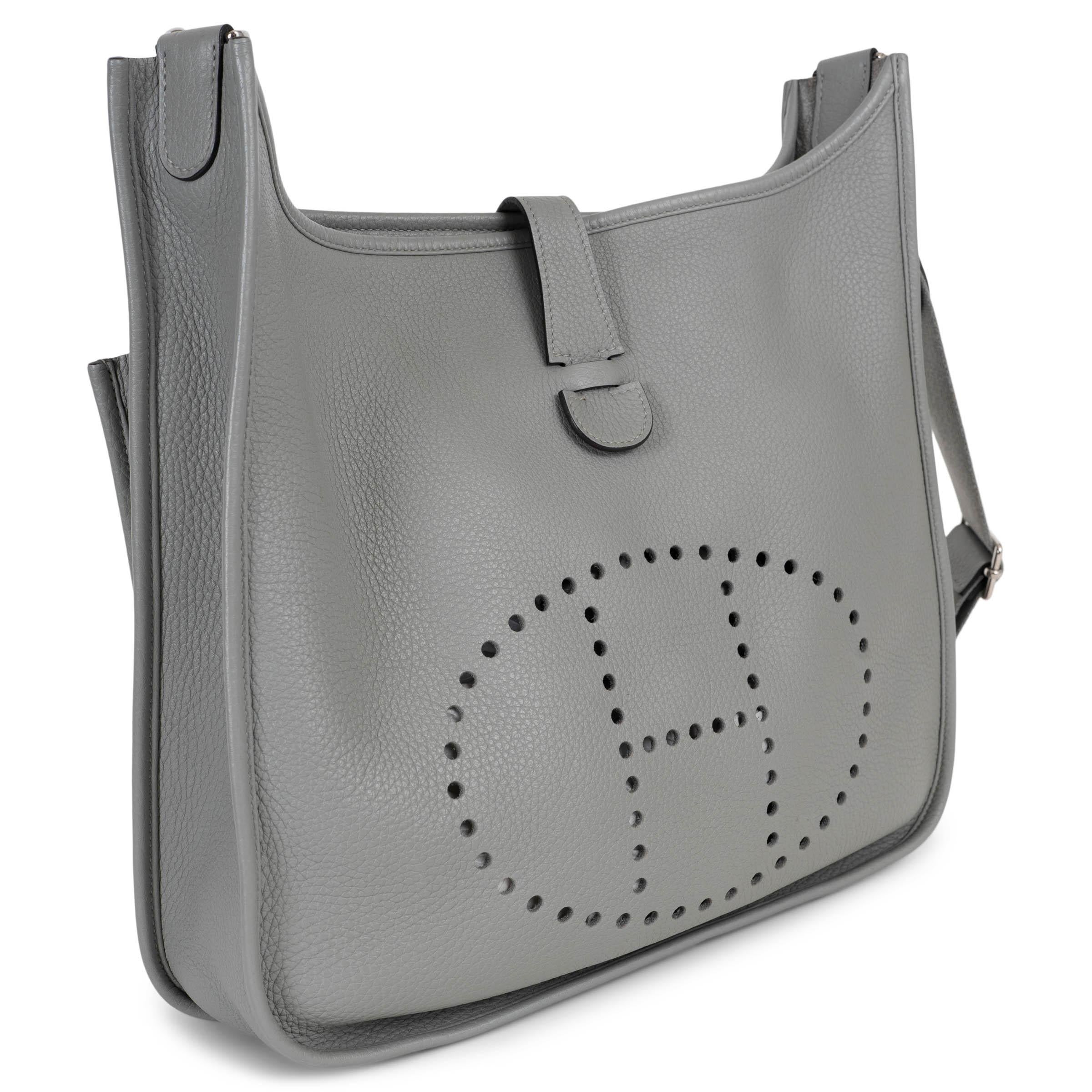 Ce sac crossbody Evelyne III 33, 100% authentique, est réalisé en cuir Clémence gris Mouette et doté de ferrures en palladium. Il présente le motif H perforé emblématique de la maison sur le devant, associé à une sangle en toile détachable et