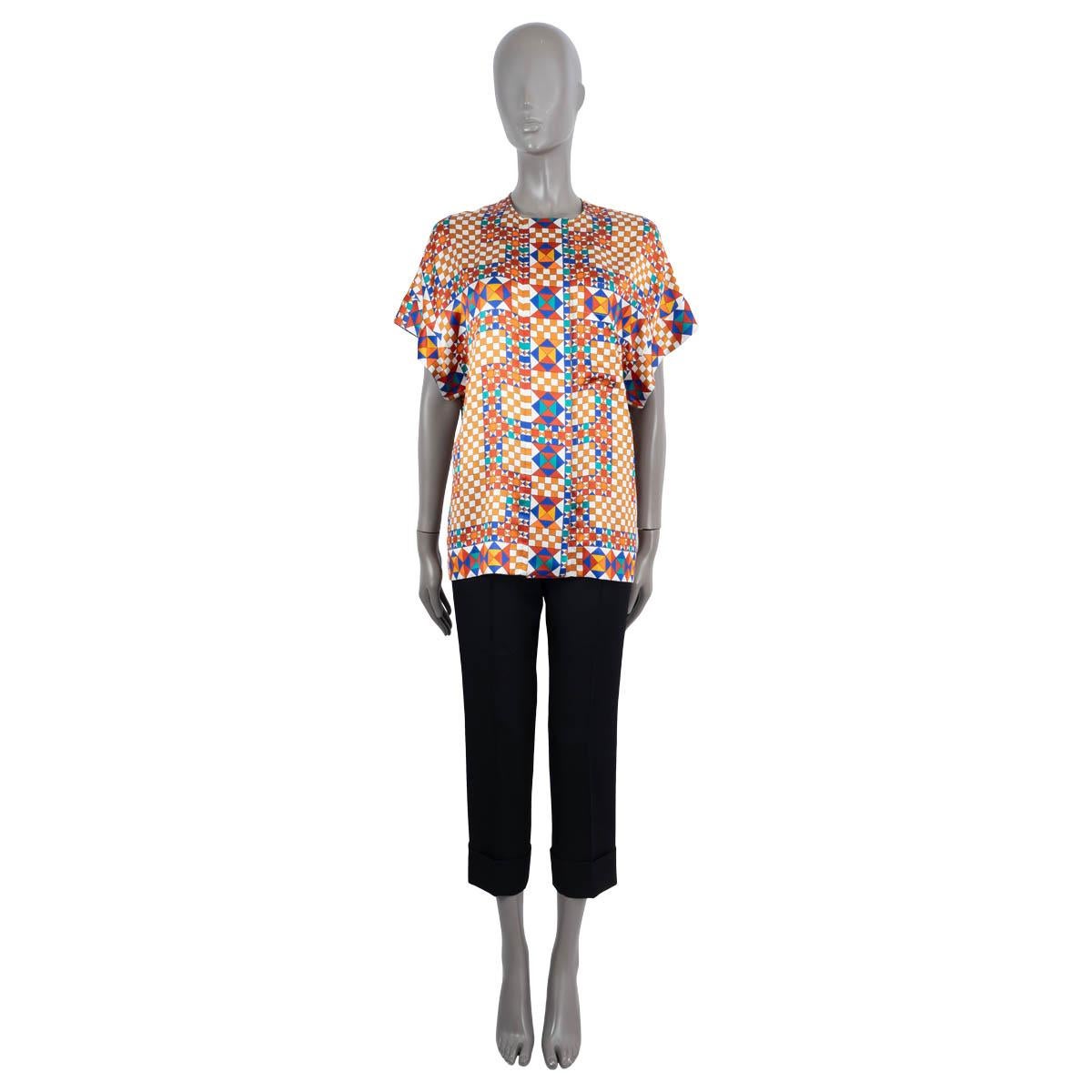 100% authentic Hermes geometric print short sleeve blouse in blue, rust, petrol, brow, orange off-white silk (100%). Features one flap pockets and a crewneck. Closes with concealed buttons on the front. Unlined. Has been worn and is in excellent