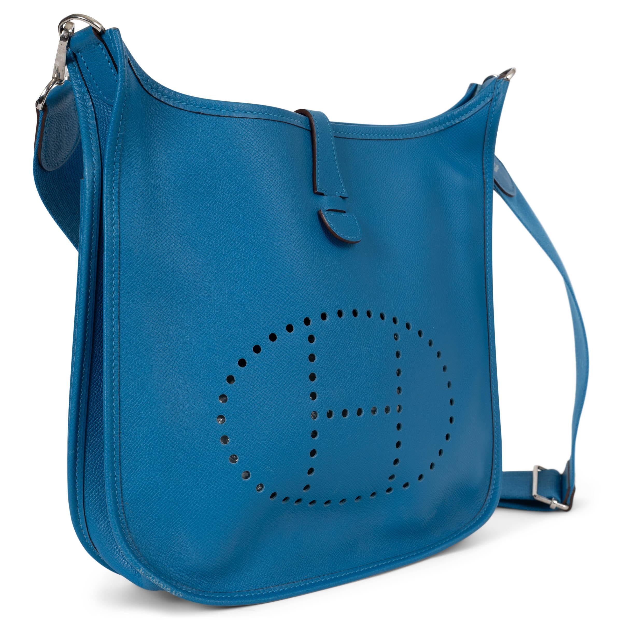 Diese 100% authentische Hermès Evelyne 29 Umhängetasche aus Bleu Izmir Epsom Leder ist ein zeitloser Klassiker, der Funktion mit müheloser Eleganz verbindet. Sie ist aus luxuriösem Clemence-Leder gefertigt, trägt das kultige perforierte 