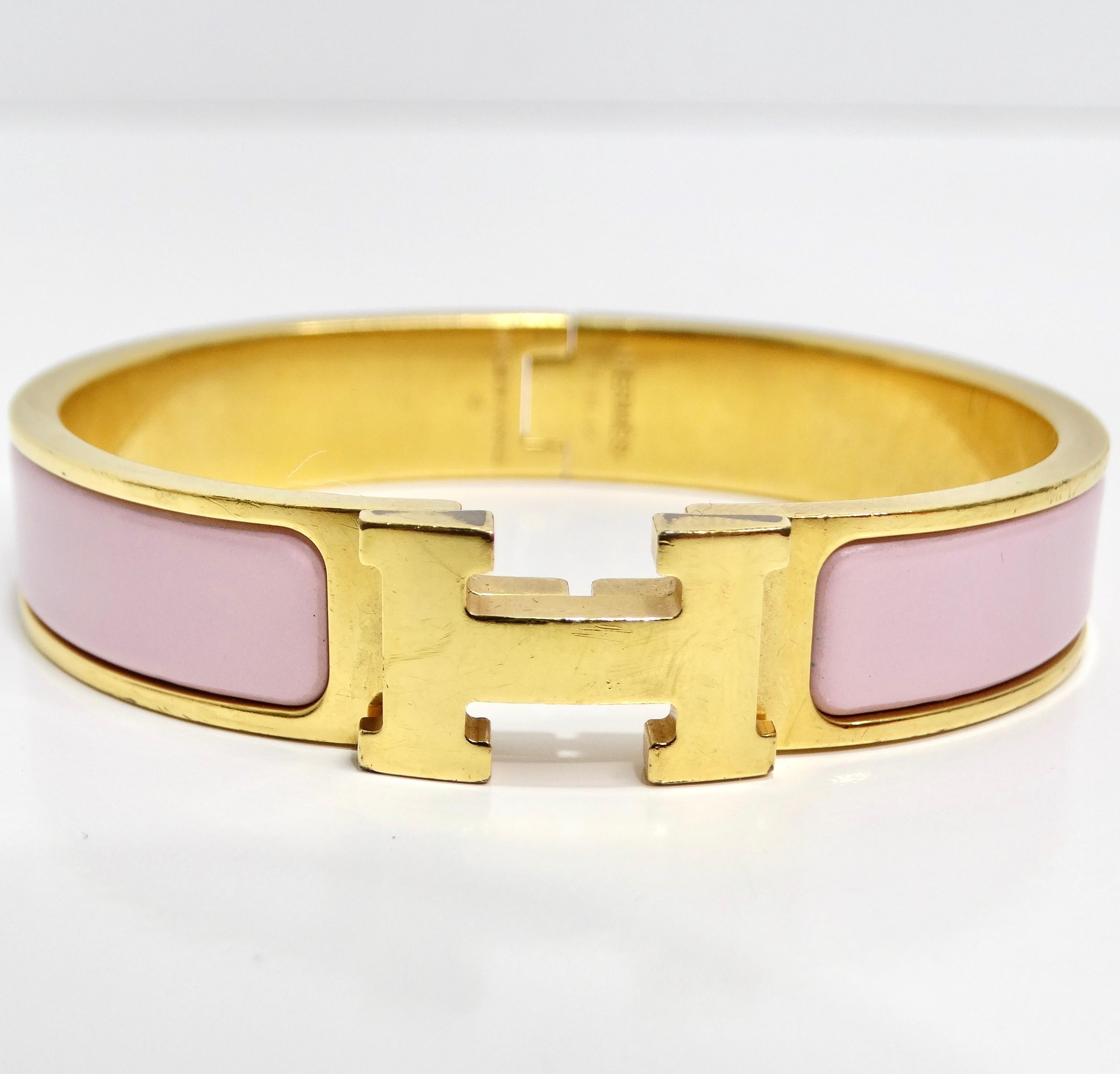 Elevate your wrist with the Hermes Narrow Enamel Clic Clac Bracelet in Light Pink – an iconic piece that seamlessly blends classic elegance with modern style. This bracelet features a thin band of plated gold with a hinge on one side, allowing for