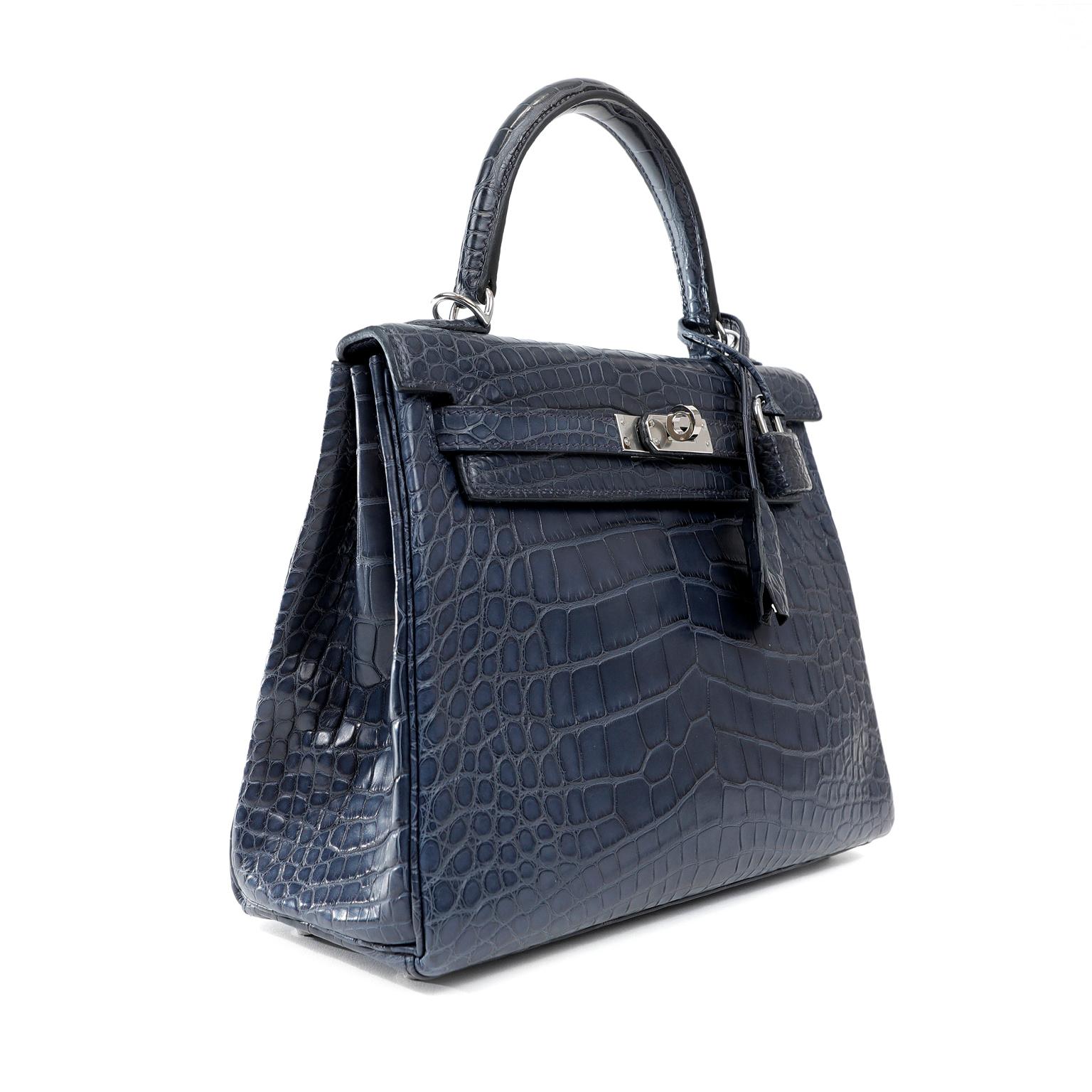 This authentic Hermès Navy Crocodile 25 cm Kelly is in pristine unworn condition.  The protective plastic remains intact on the hardware.   Hermès bags are considered the ultimate luxury item worldwide.  Each piece is handcrafted with waitlists that