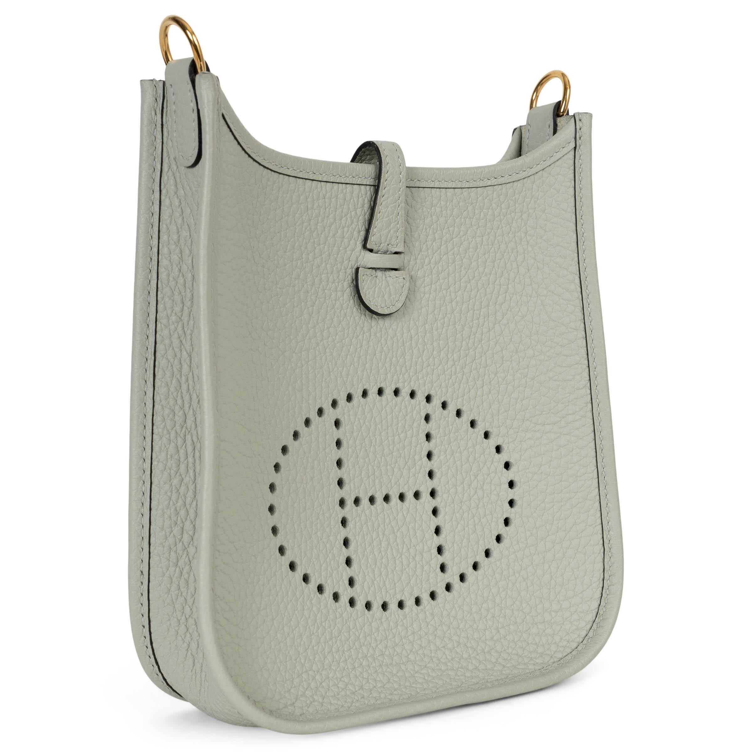 This 100% authentic Hermès Evelyne 16 TPM Crossbody Bag in Gris Neve (light grey) Taurillon Clemence leather is a timeless addition to any collection. Featuring the iconic perforated 