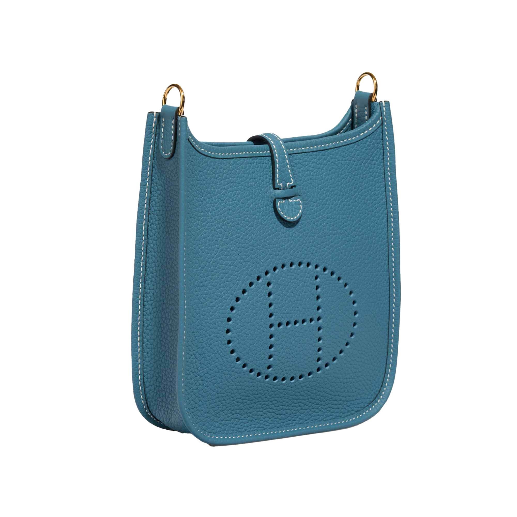 This 100% authentic Hermès Evelyne 16 TPM Crossbody Bag is crafted from New Bleu Jean (jeans blue) Taurillon Clemence leather and features a matching uni wool sangle strap. The design includes the signature perforated leather 