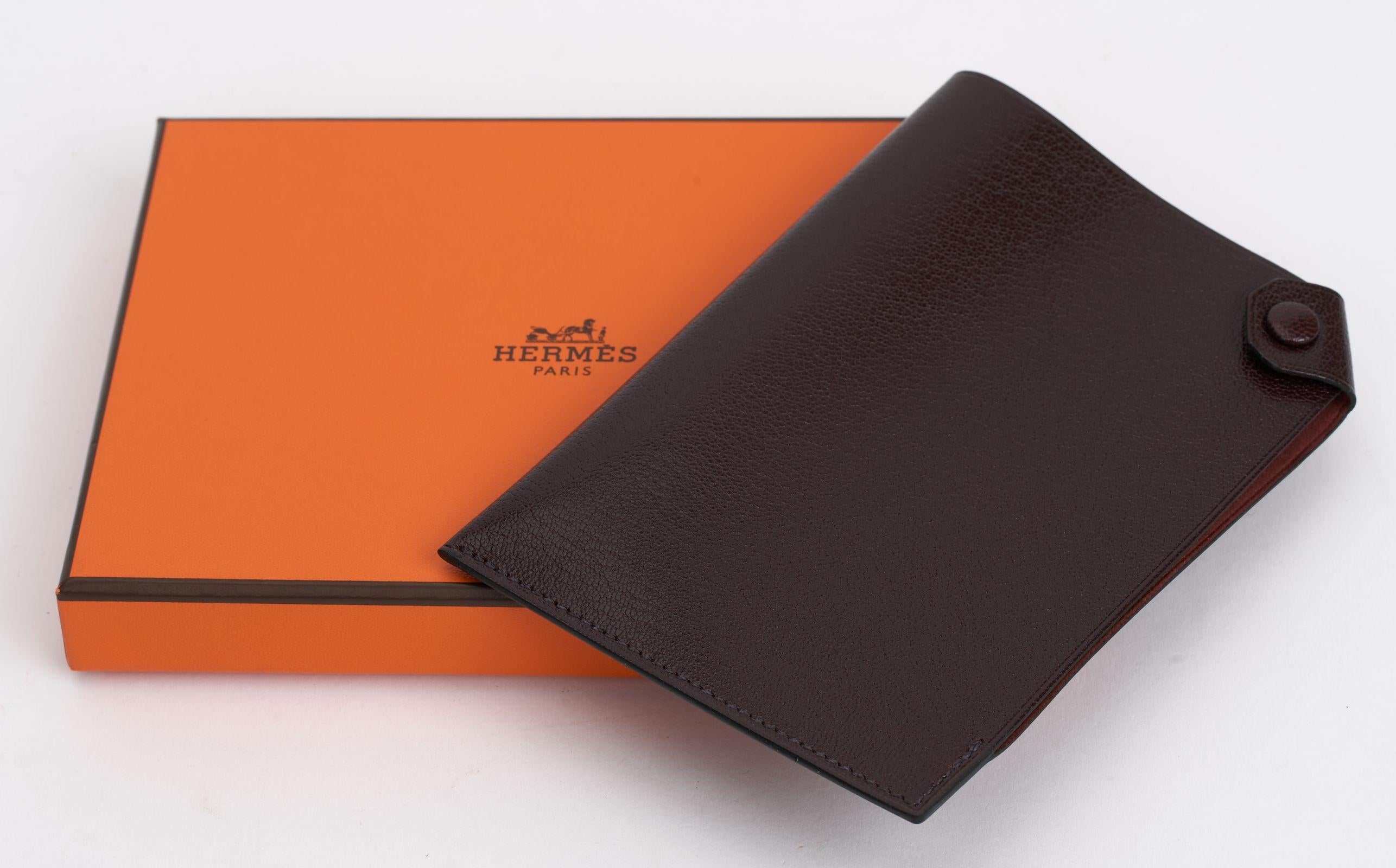 This Hermès Passport holder in chevre (goatskin) calfskin features a snap closure that is palladium plated. Classic rouhe H color. The slim design is perfect for travel. Comes with the original box. Brand new in unused condition.