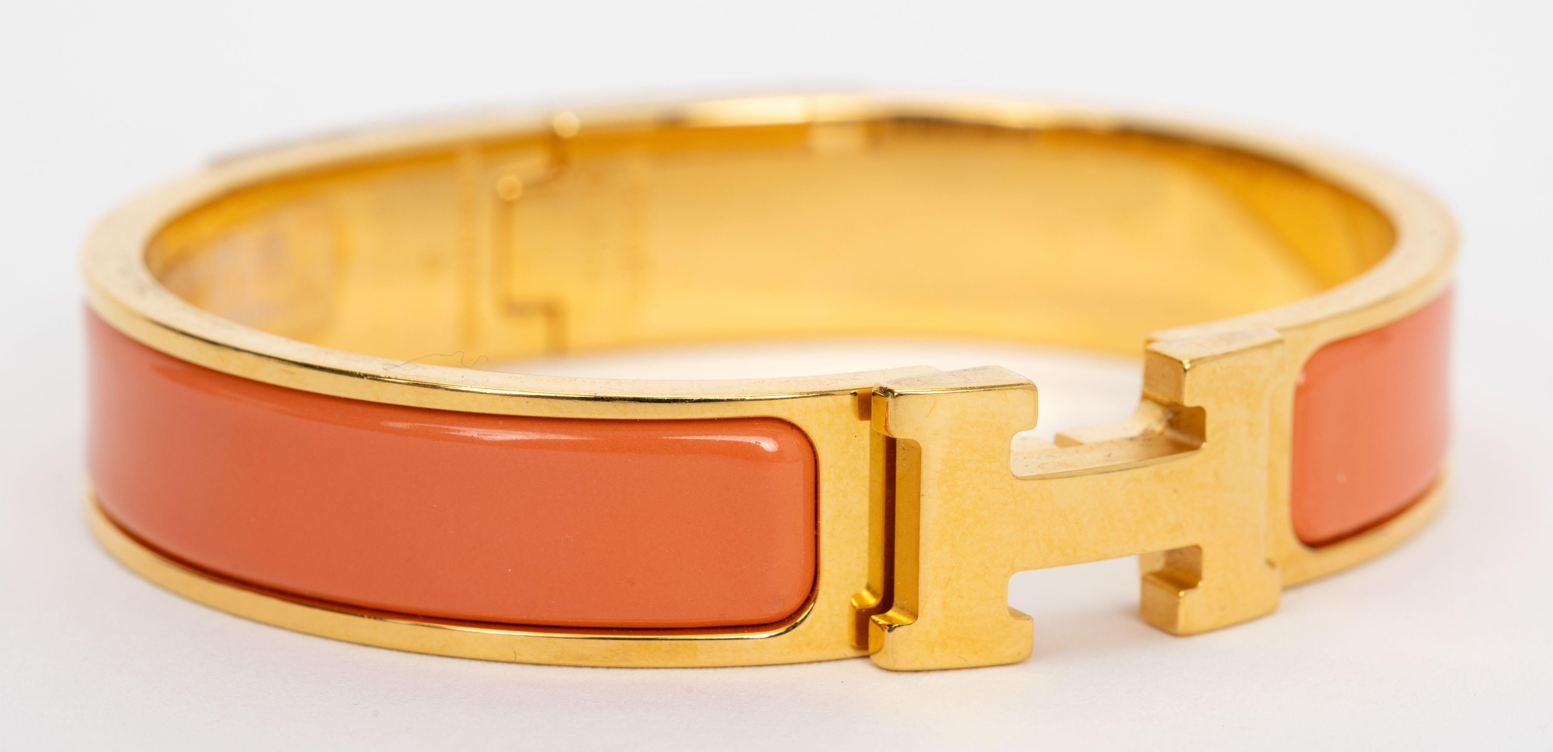 Le bracelet Hermes Clic Clac H, étroit,  en émail pêche melba, avec des accessoires plaqués or.
Taille PM, neuf, non porté, livré avec une pochette en velours.