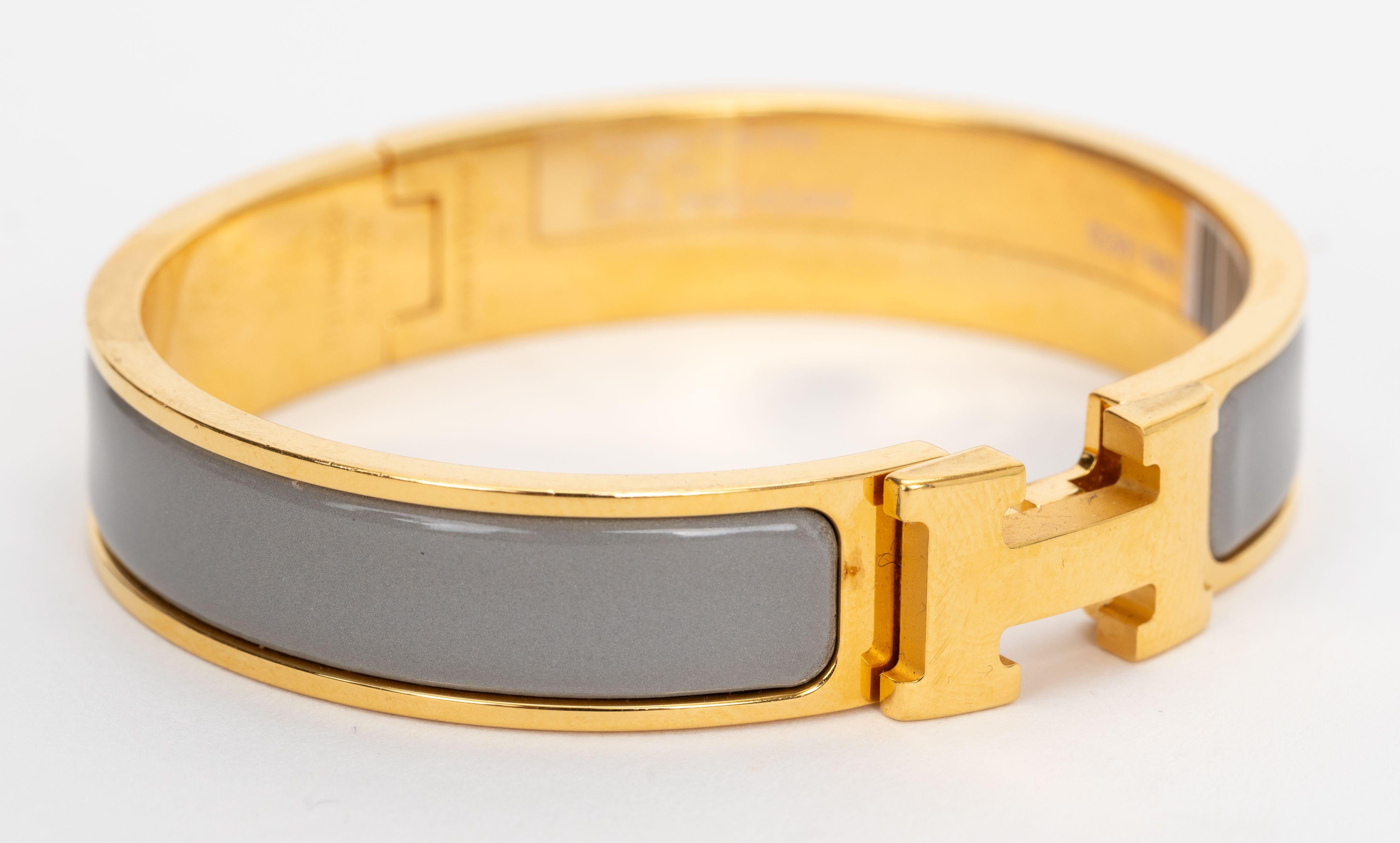 Le bracelet Hermes Clic clac H, étroit, en macadamia gris émaillé avec des attaches plaquées or.
Taille PM, neuf, non porté, livré avec une pochette en velours.