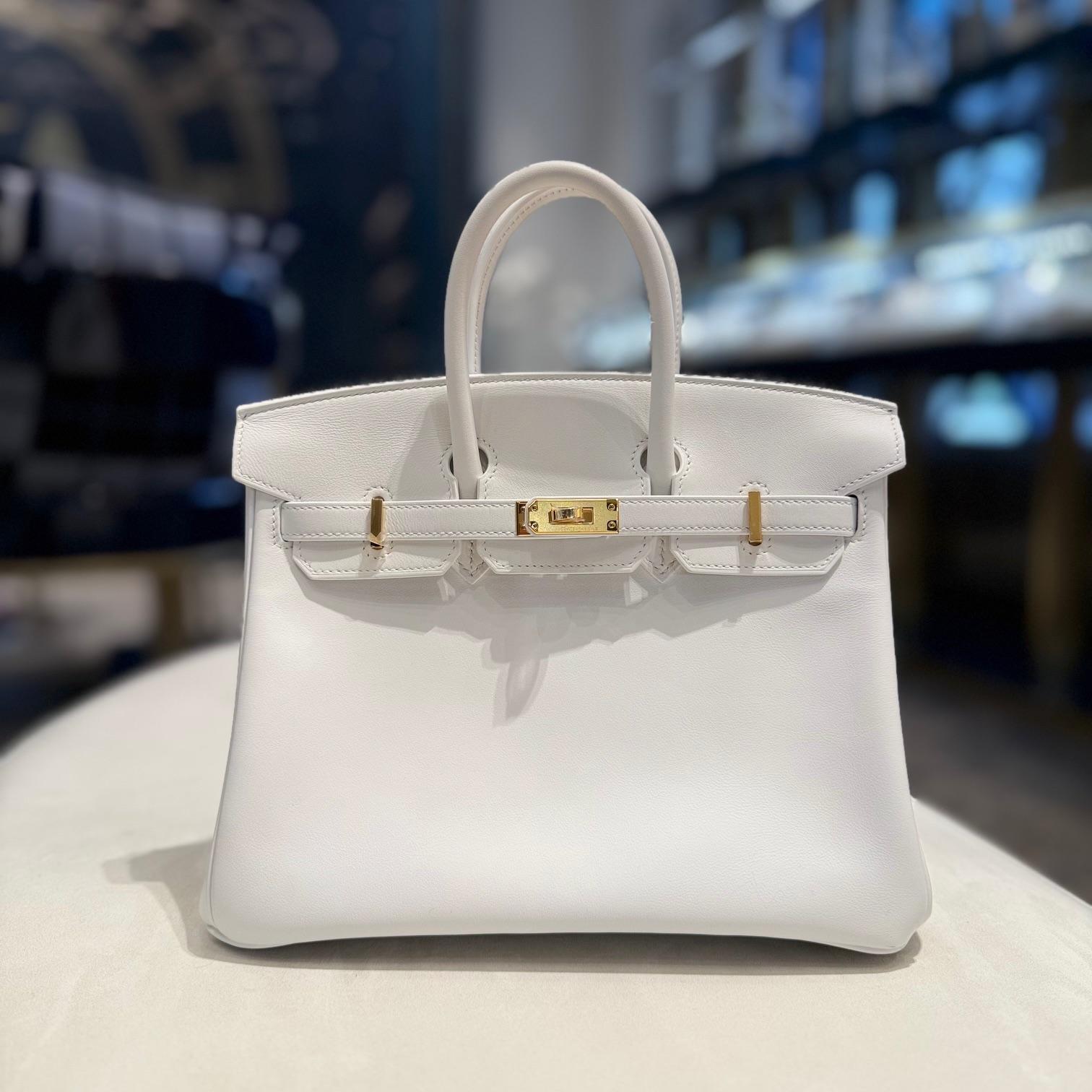 La Birkin 25 bianca di Hermès in pelle Swift è un pezzo elegante e senza tempo. La tonalità bianca esalta la consistenza liscia e morbida della pelle Swift, mentre le finiture dorate (GHW) aggiungono un tocco di lusso. Compatta ma funzionale, questa
