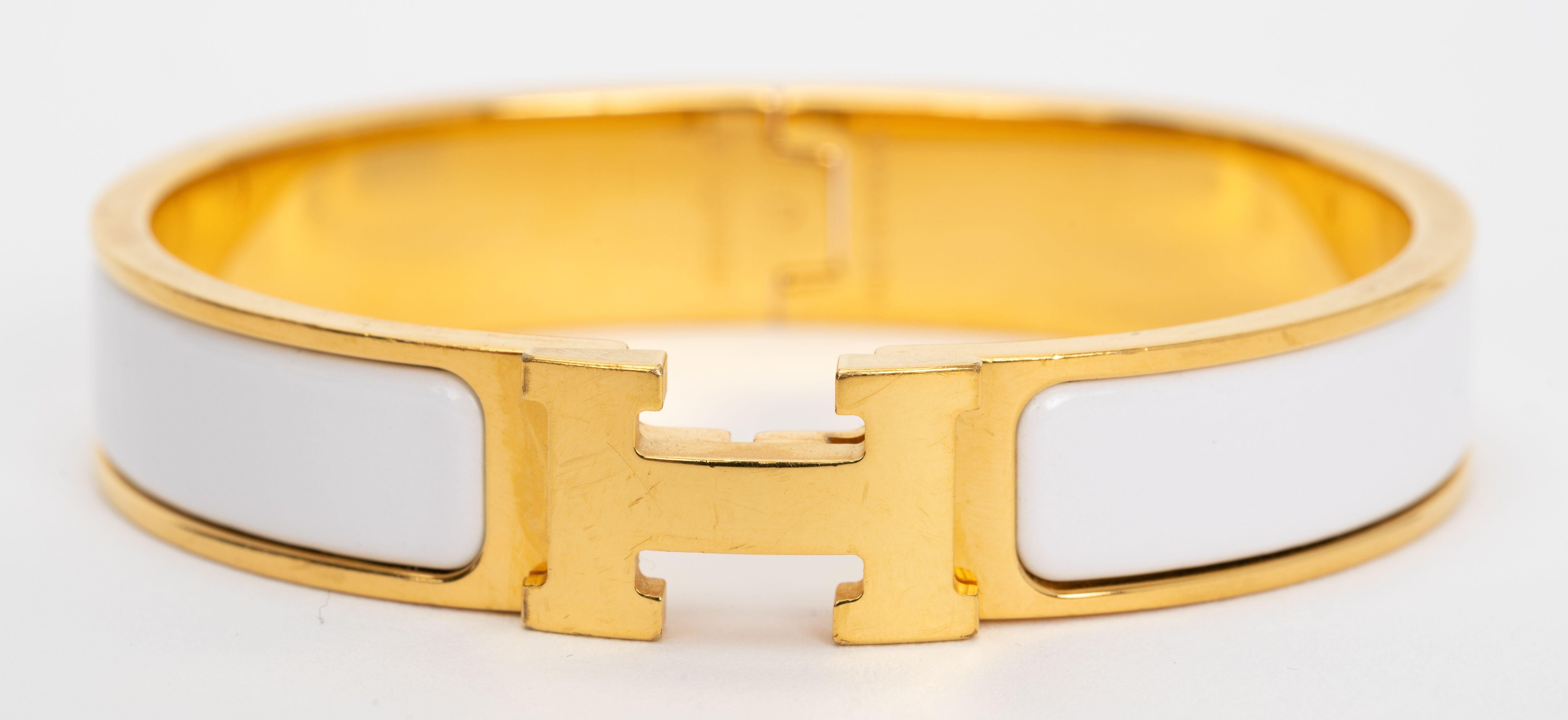 Le Clic Clac H d'Hermes, bracelet étroit en émail blanc avec des attaches plaquées or.
Taille PM, neuf, non porté, livré avec une pochette en velours.