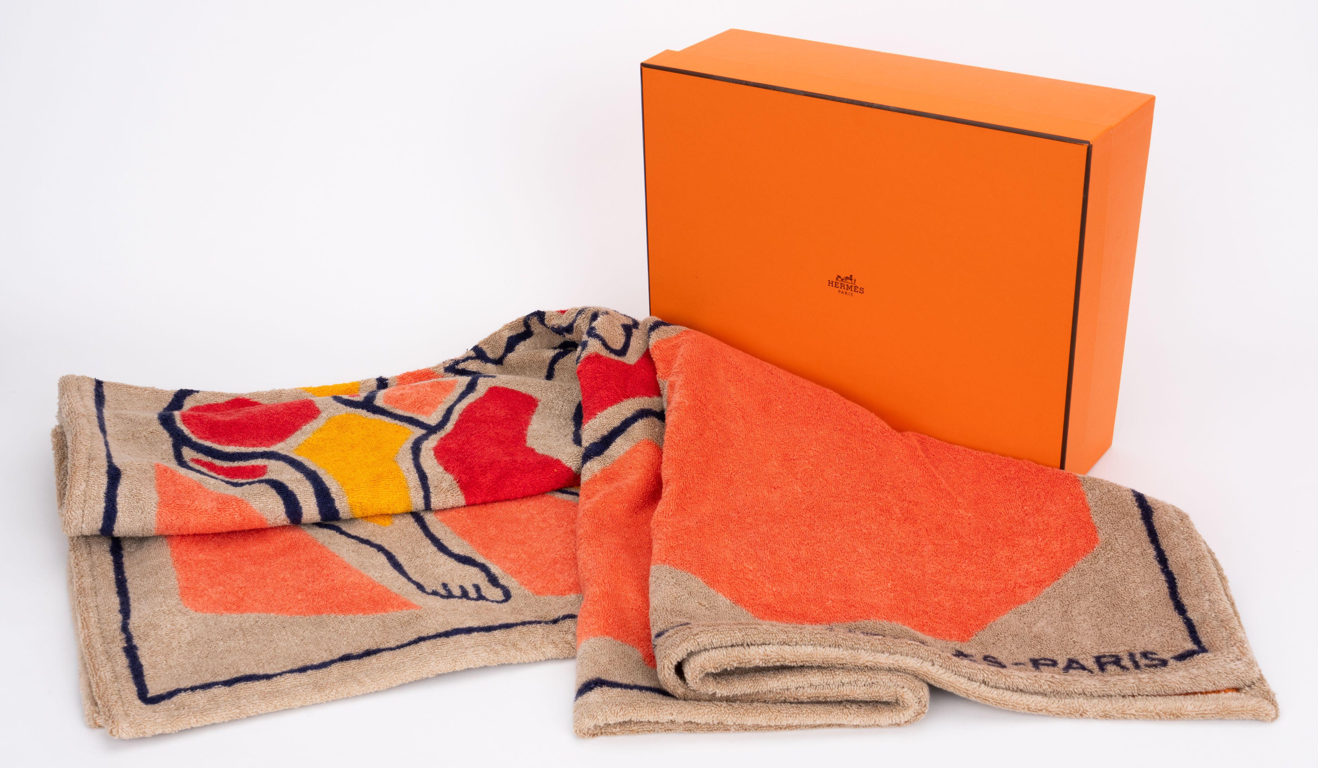 Serviette de plage Hermès à motif géométrique de chevaux et de personnages. Combinaison de couleurs orange, taupe et noir. 100% coton. Livré avec sa boîte d'origine.