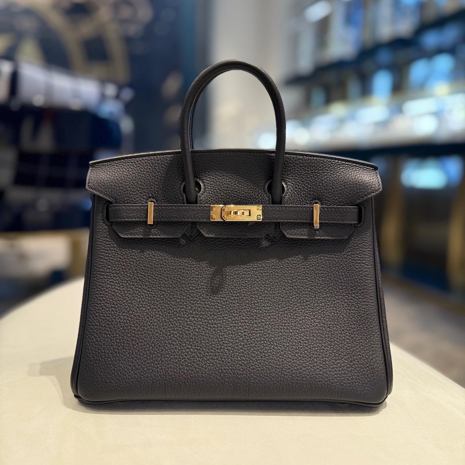 Jewels Aficionado offers the Hermès Birkin 25 in Noir Togo leather, a timeless and sophisticated piece. The deep black hue enhances its sleek appeal, while Togo leather provides a textured, durable finish with a soft yet structured silhouette.